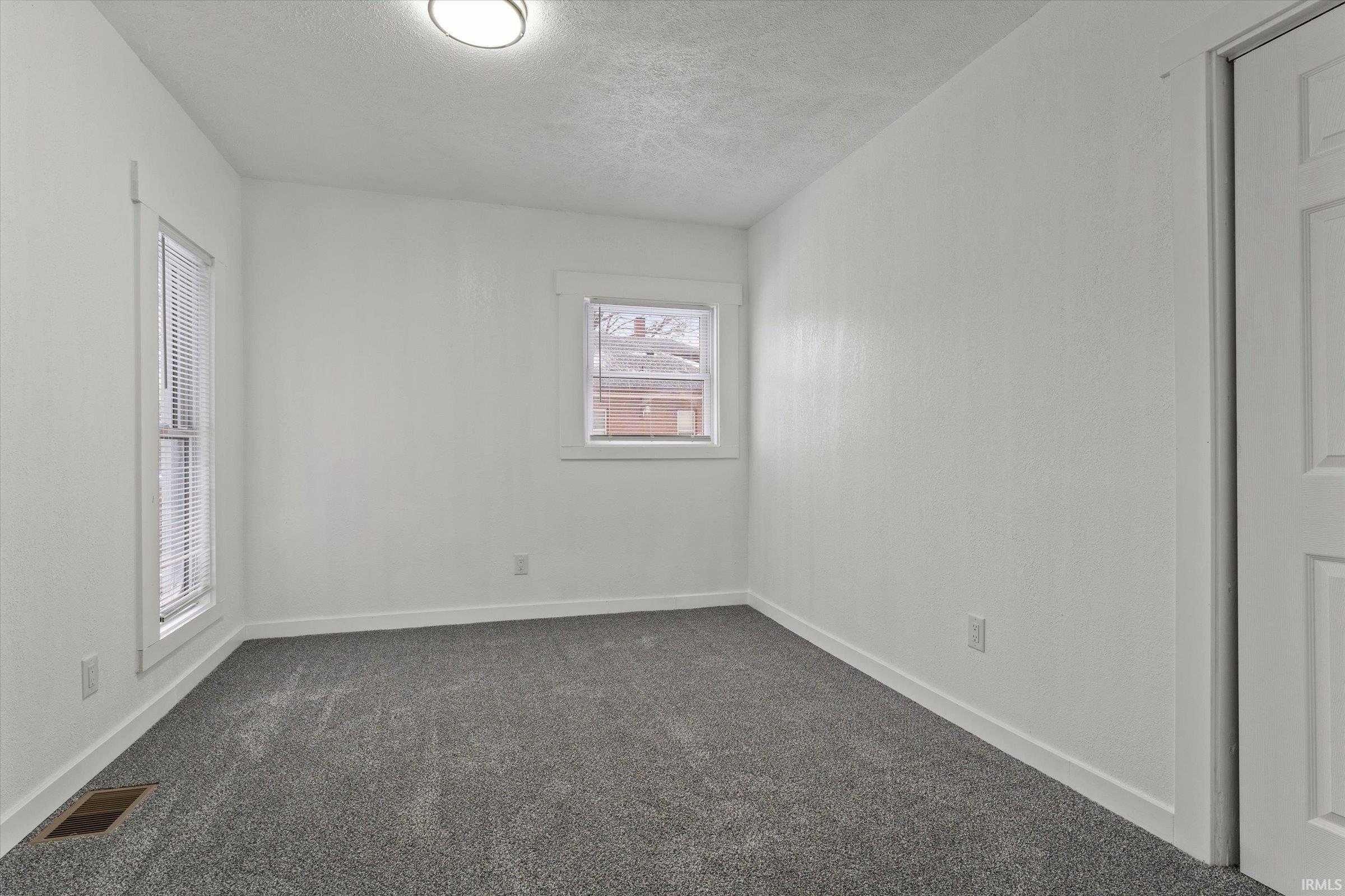 Spare room with dark colored carpet and a textured ceiling