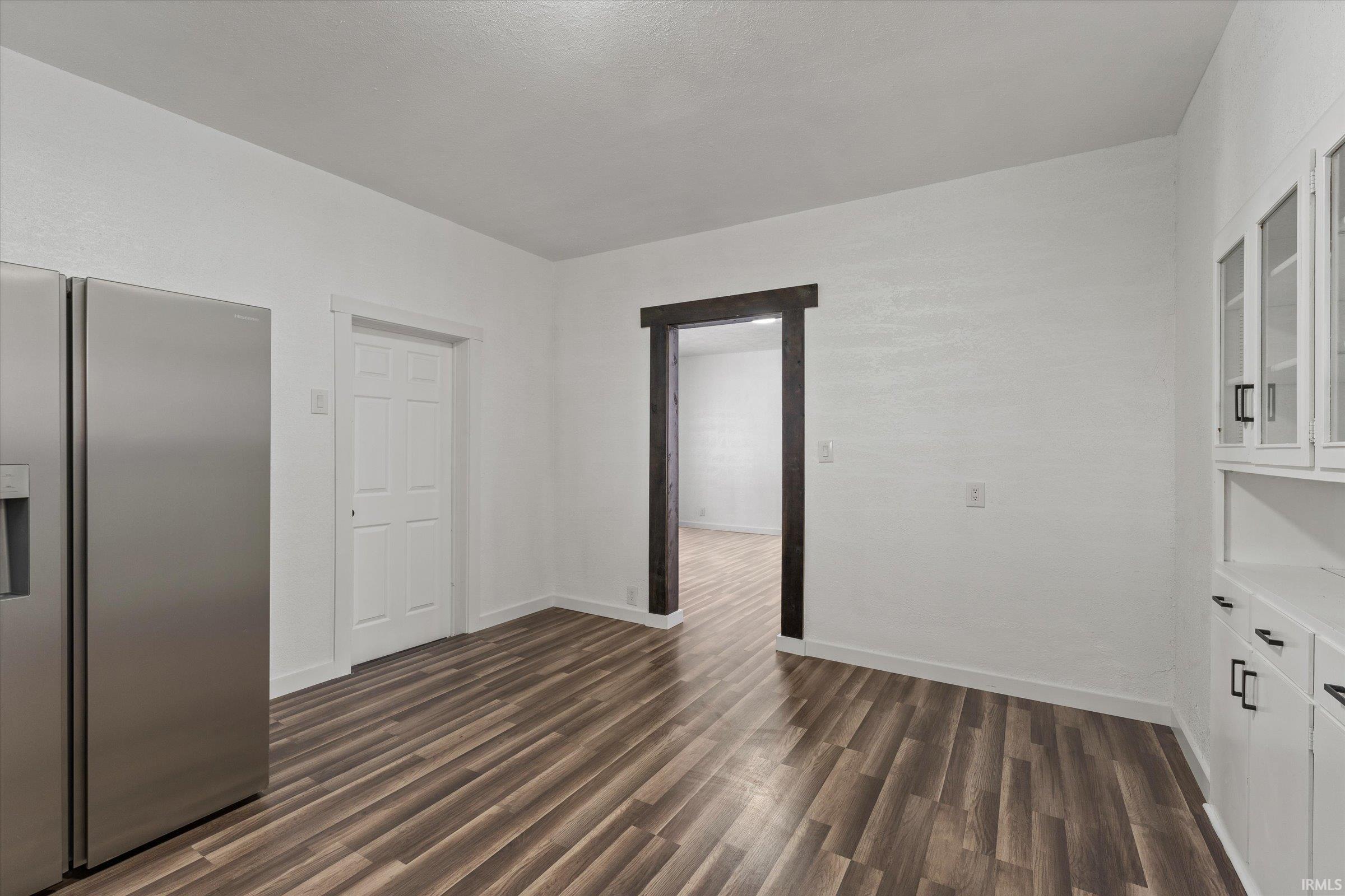 Unfurnished dining area featuring dark wood-style floors and baseboards