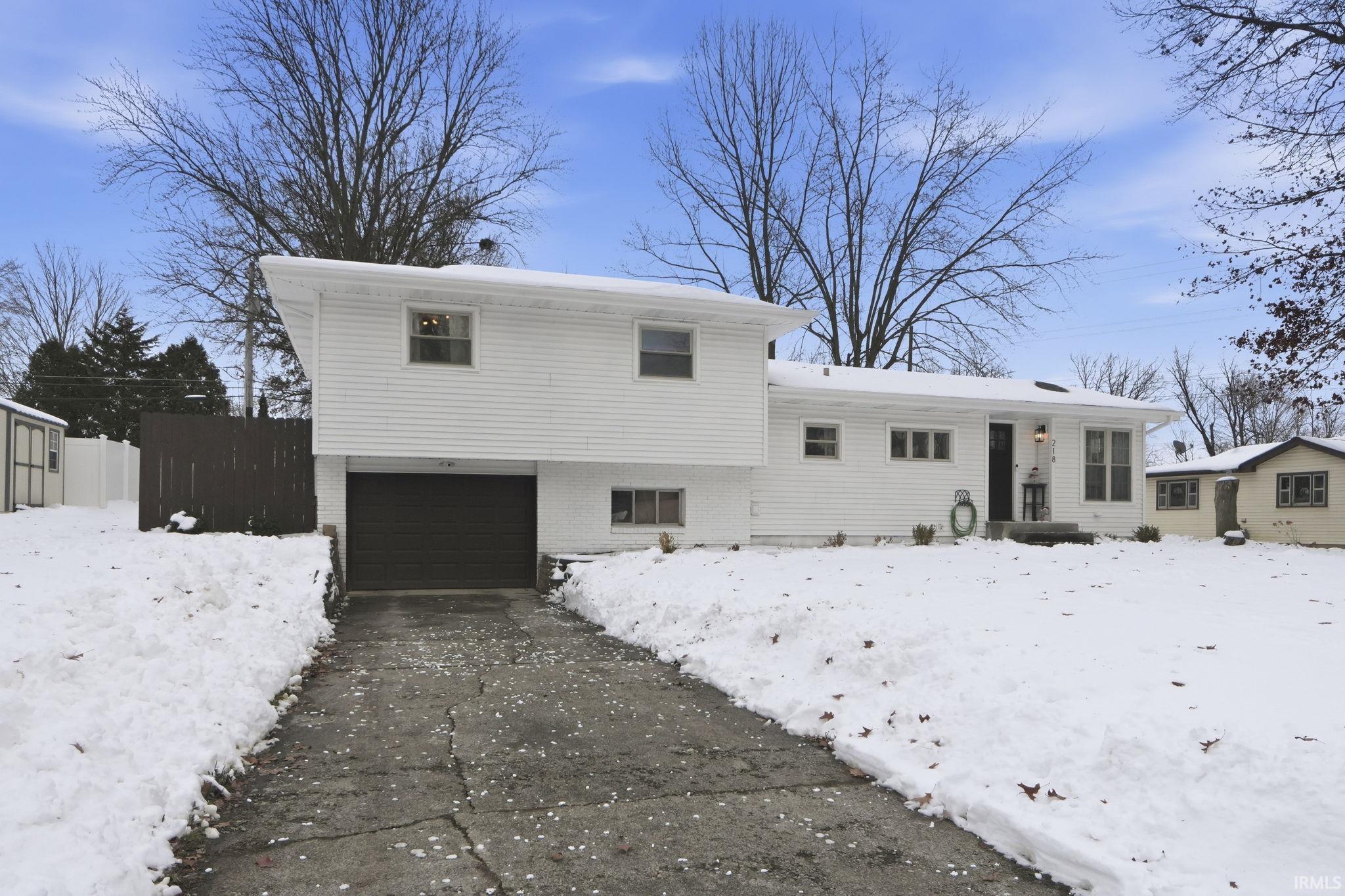 Snow covered house with brick siding and a garage