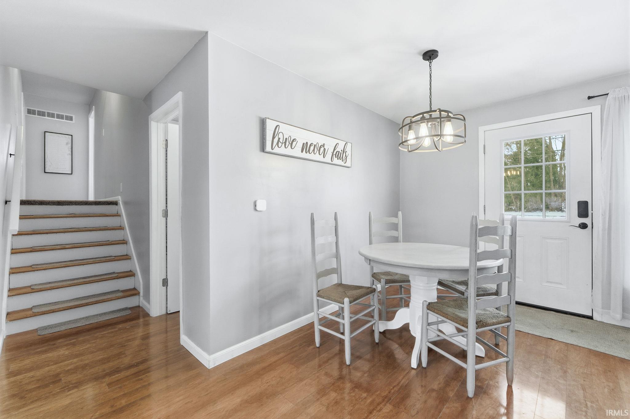Dining area featuring light wood finished floors, stairs, and a chandelier