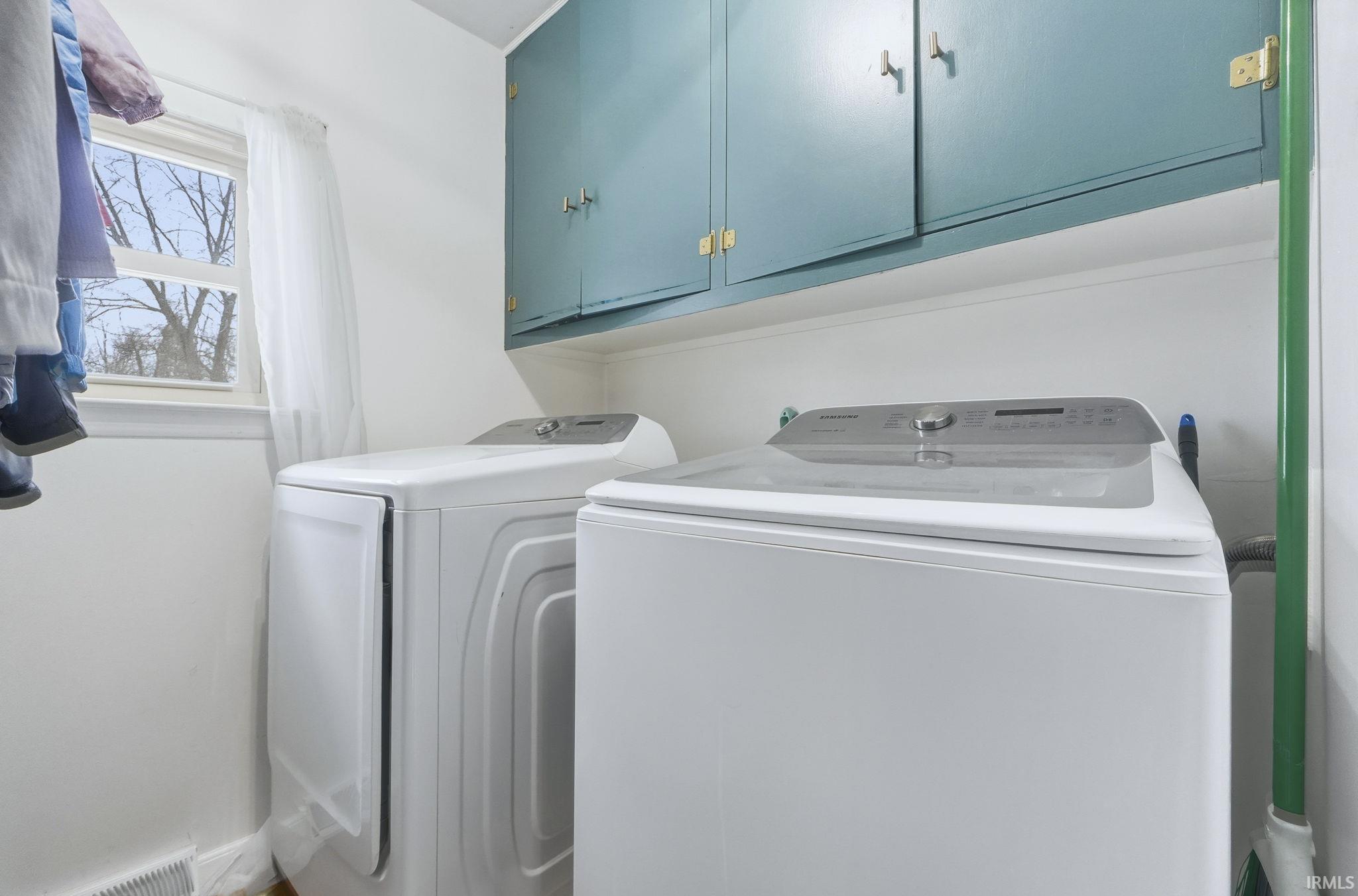 Washroom featuring cabinet space and washing machine and dryer