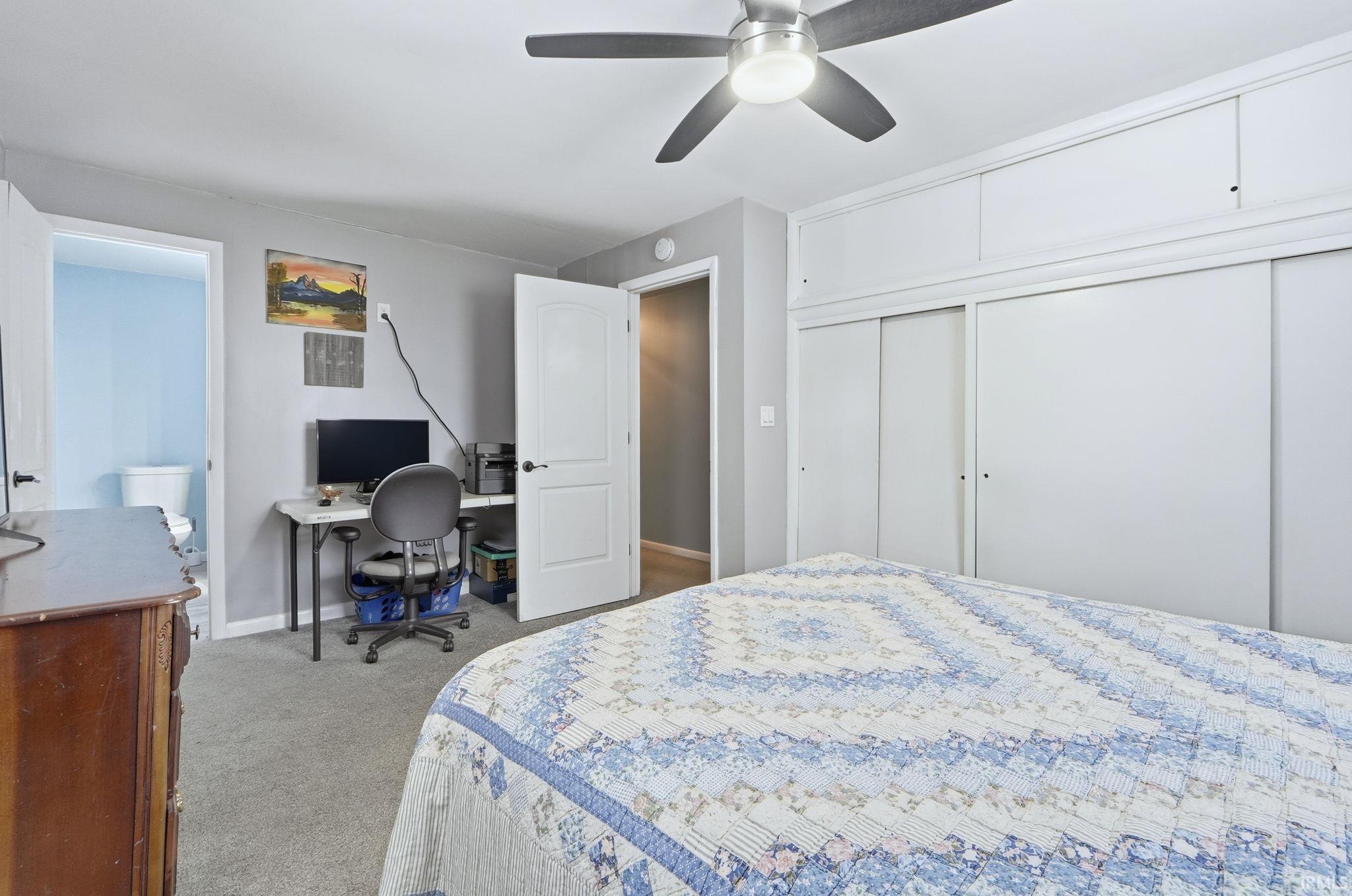 Carpeted bedroom featuring a desk, a closet, and a ceiling fan