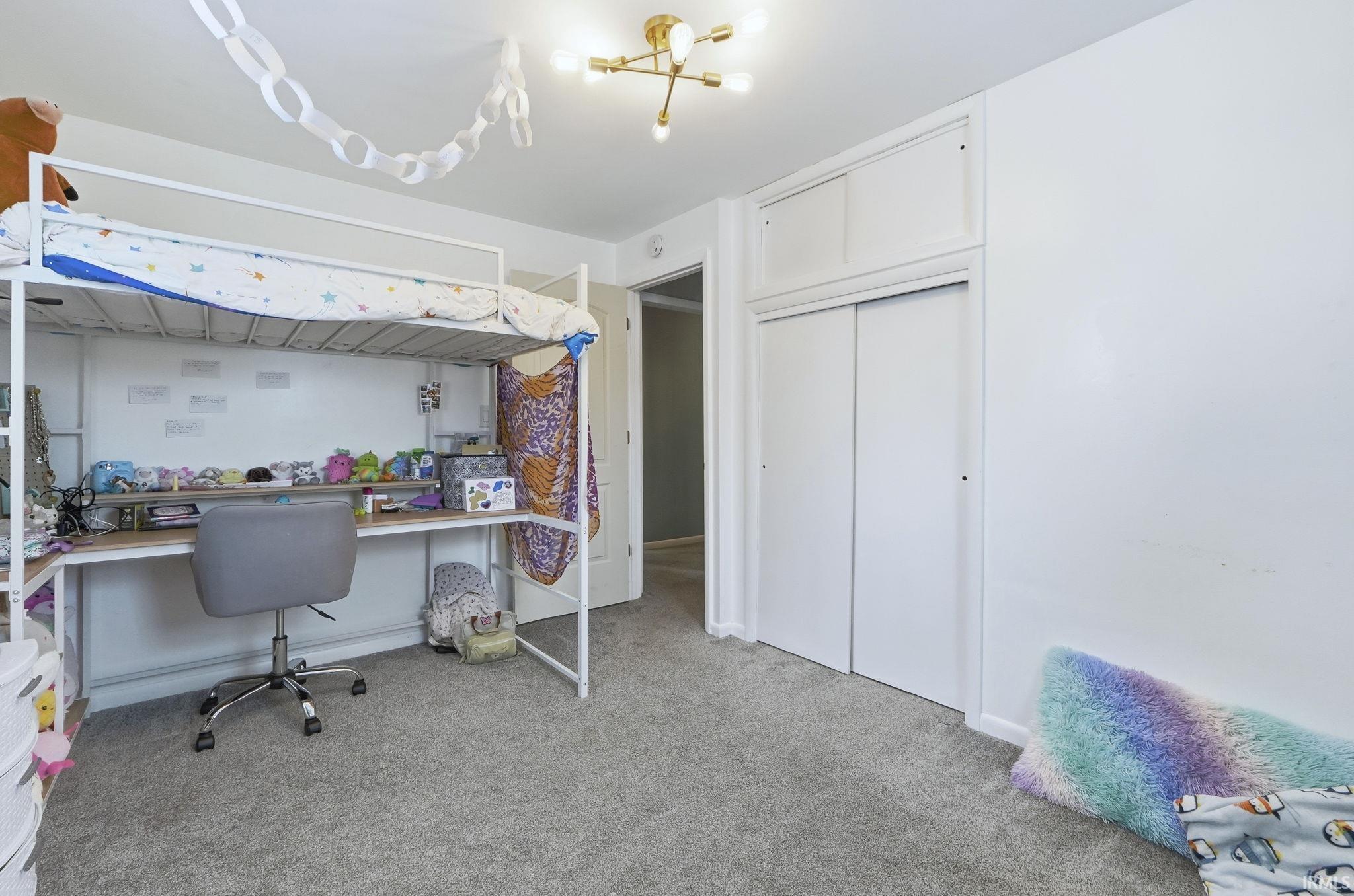 Bedroom featuring built in desk, light carpet, and a closet