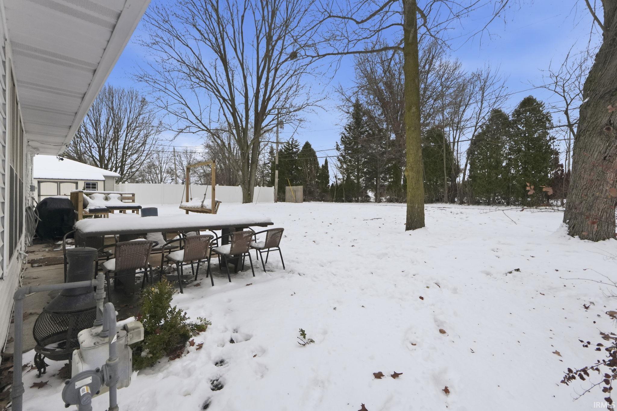 Yard layered in snow with a patio area and outdoor dining area