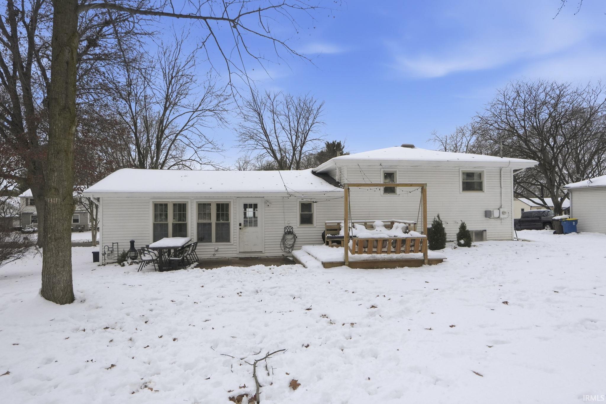 Snow covered rear of property with a wooden deck