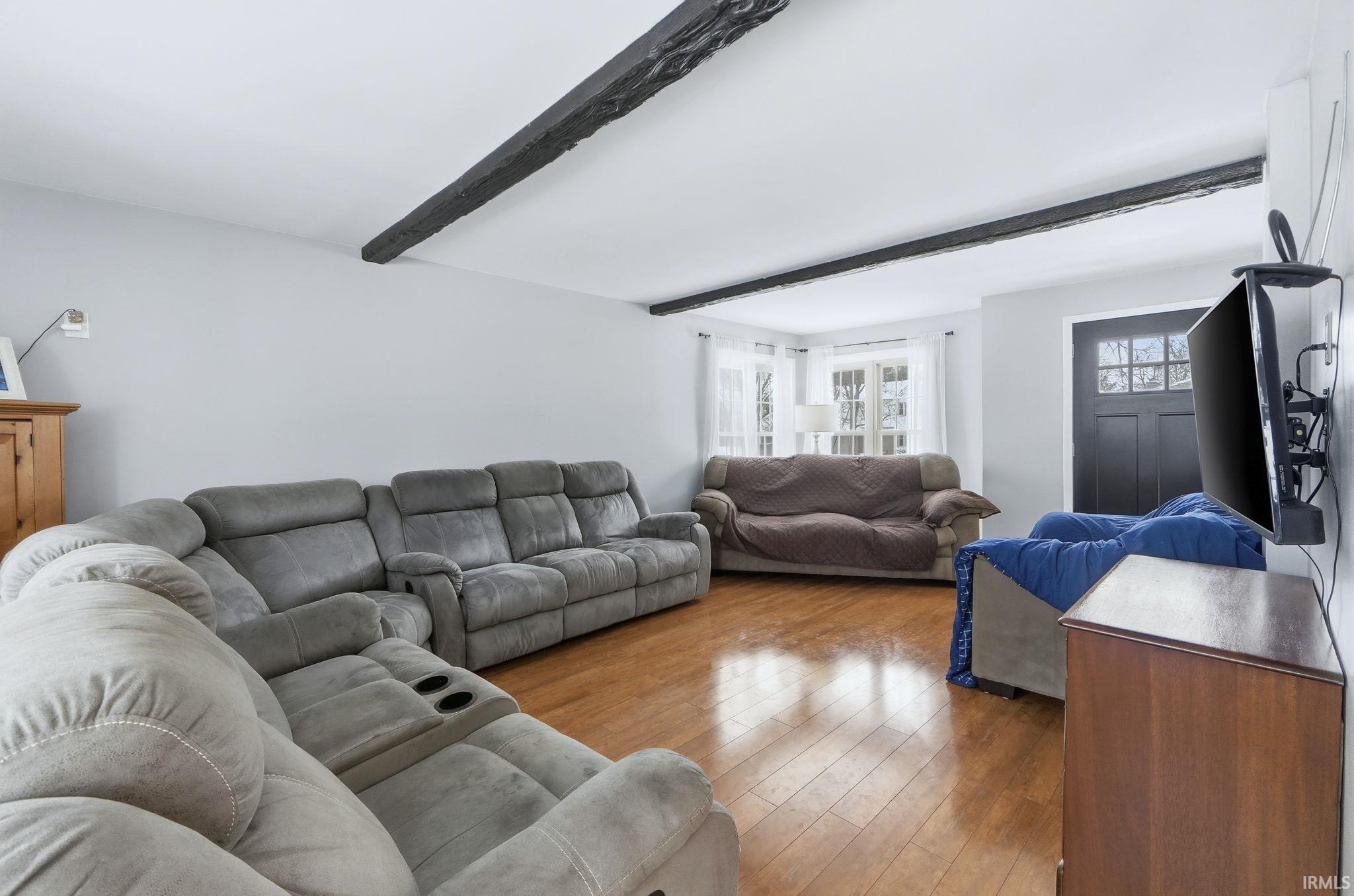Living area with hardwood / wood-style floors and beam ceiling