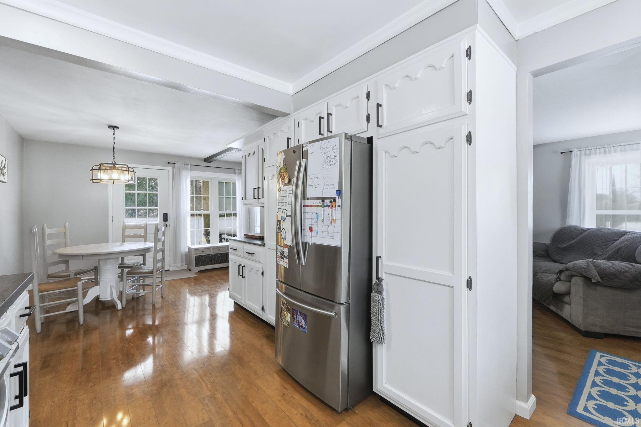 Kitchen with freestanding refrigerator, healthy amount of natural light, white cabinets, and dark wood-style flooring