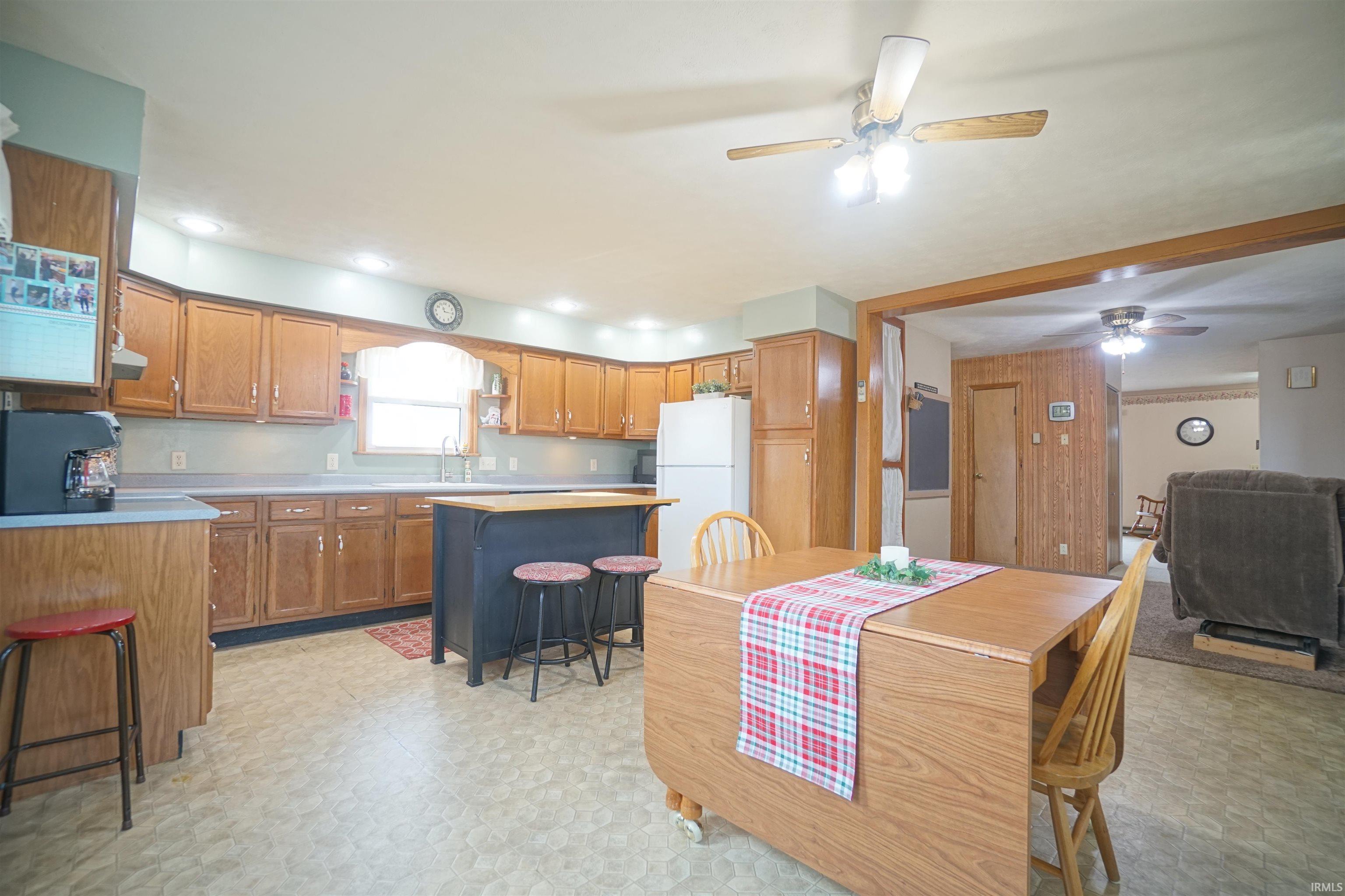Kitchen featuring brown cabinetry, a kitchen breakfast bar, light flooring, light countertops, and freestanding refrigerator