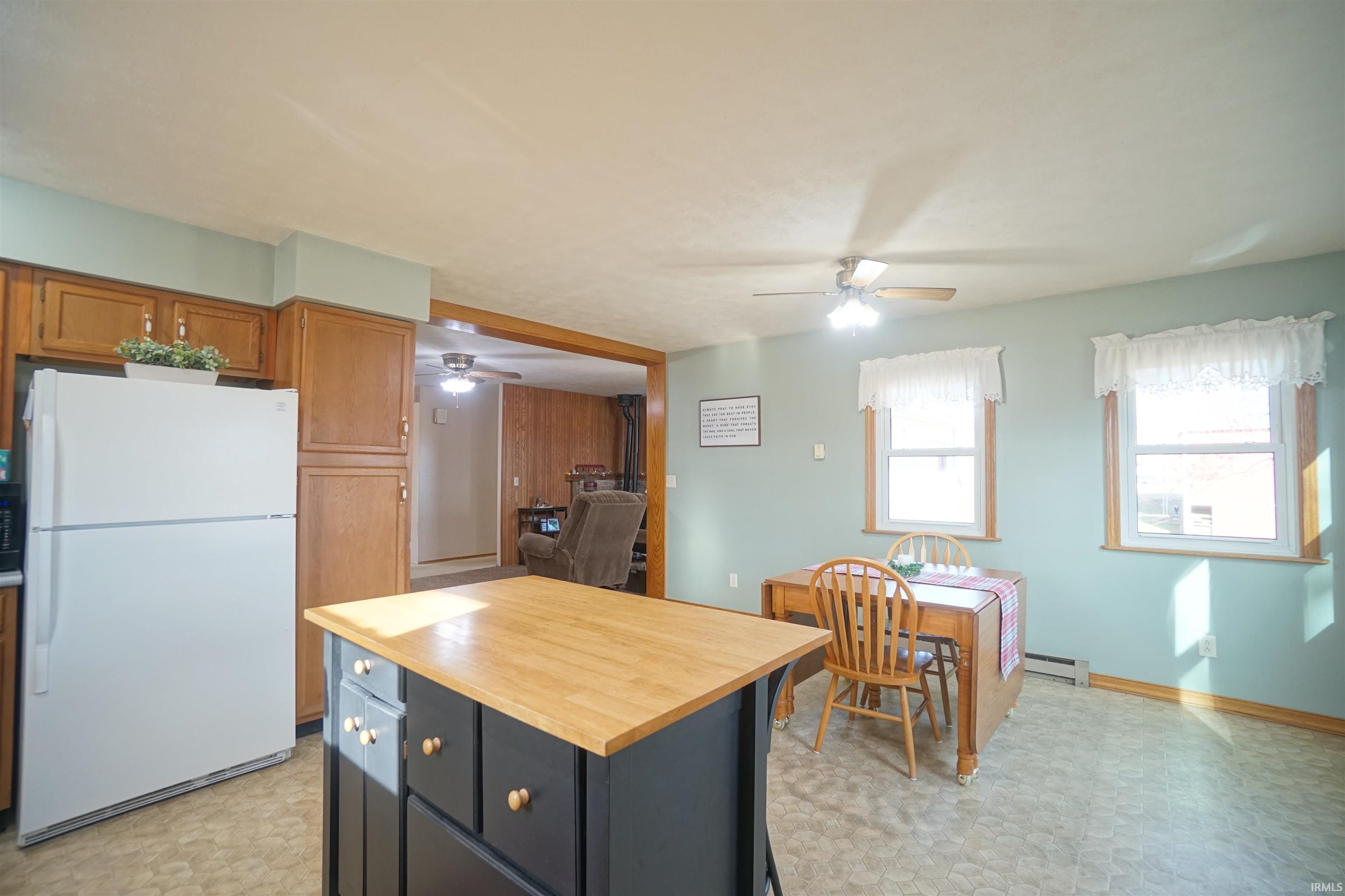 Kitchen with light flooring, freestanding refrigerator, butcher block countertops, a center island, and brown cabinetry