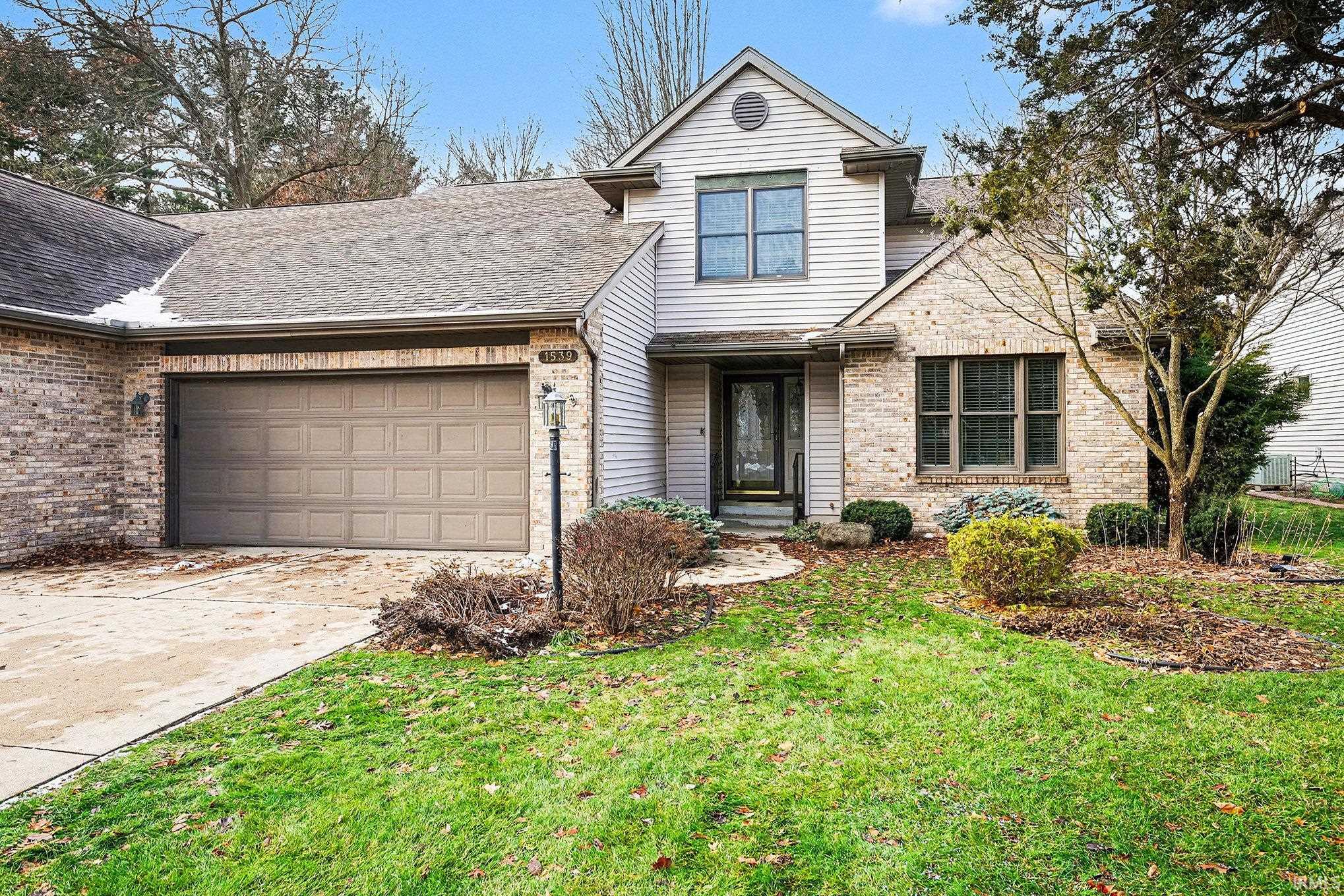 Traditional home featuring brick siding, a shingled roof, and a front lawn