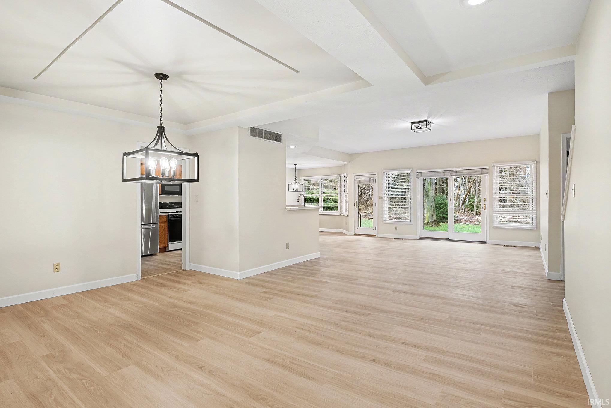 Unfurnished living room with light wood-style floors, a chandelier, plenty of natural light, and recessed lighting