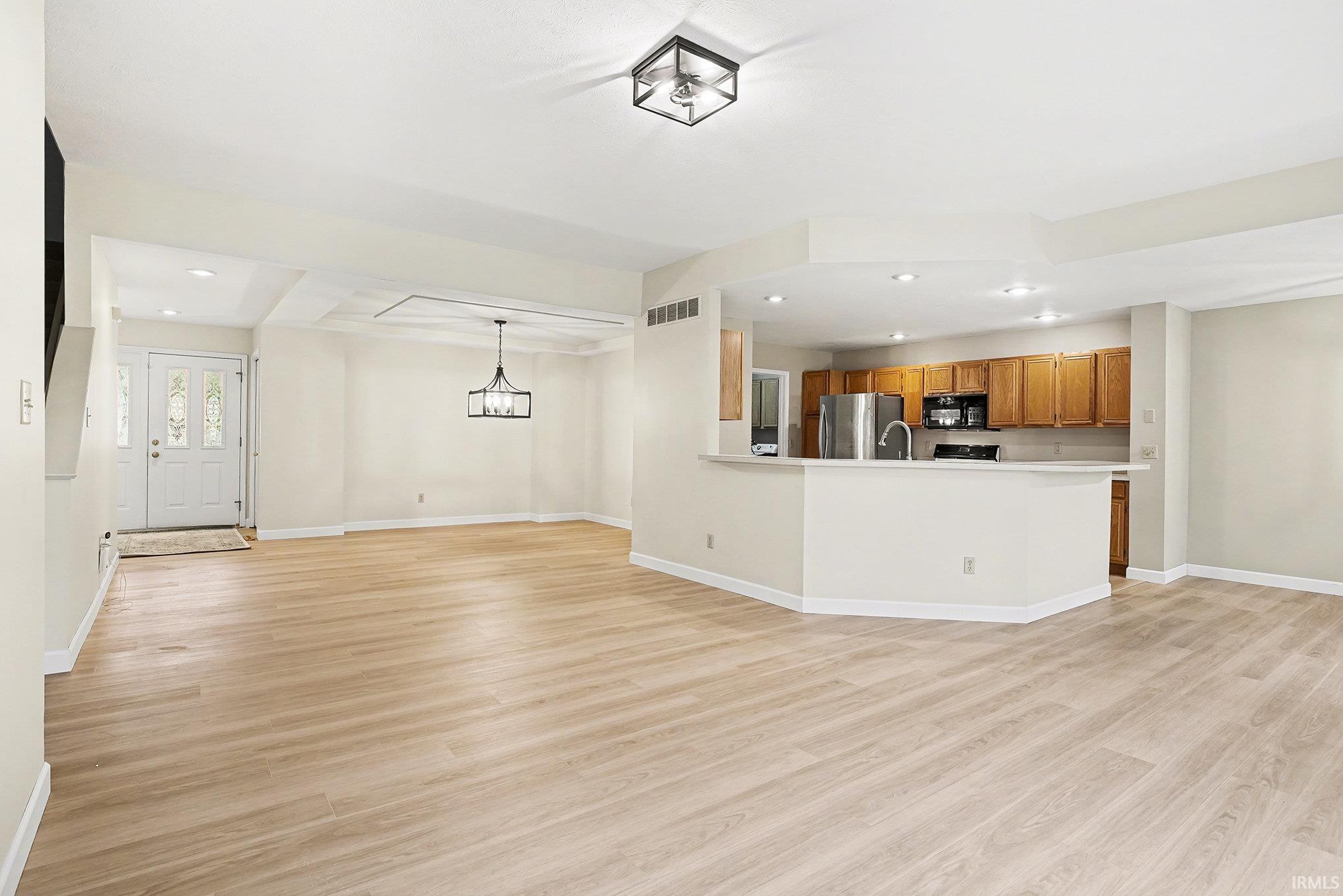 Unfurnished living room featuring recessed lighting, light wood finished floors, and a chandelier