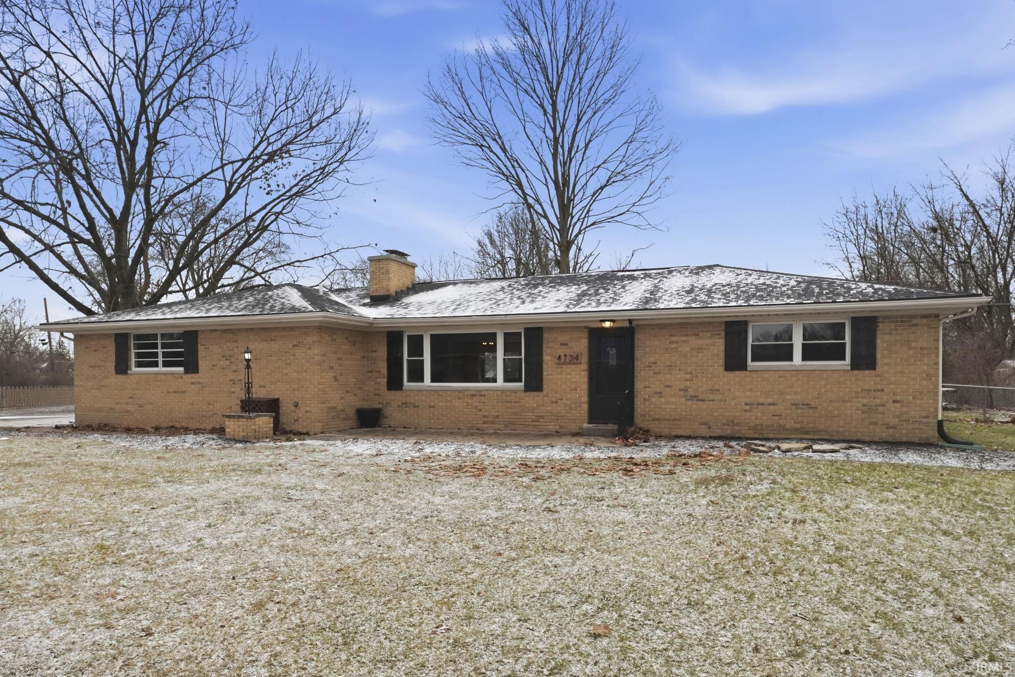 View of front of home with brick siding and a chimney