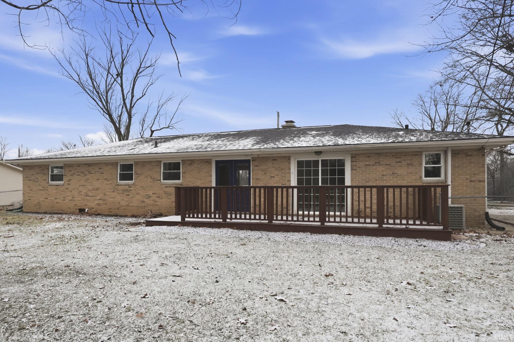 Back of property with brick siding, a wooden deck, and a shingled roof