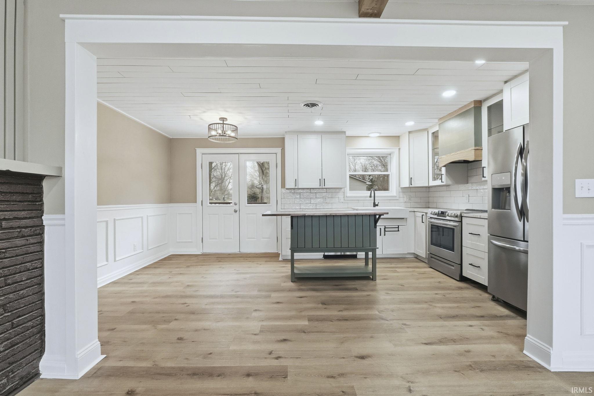 Kitchen with white cabinetry, a wainscoted wall, a decorative wall, light countertops, and a breakfast bar