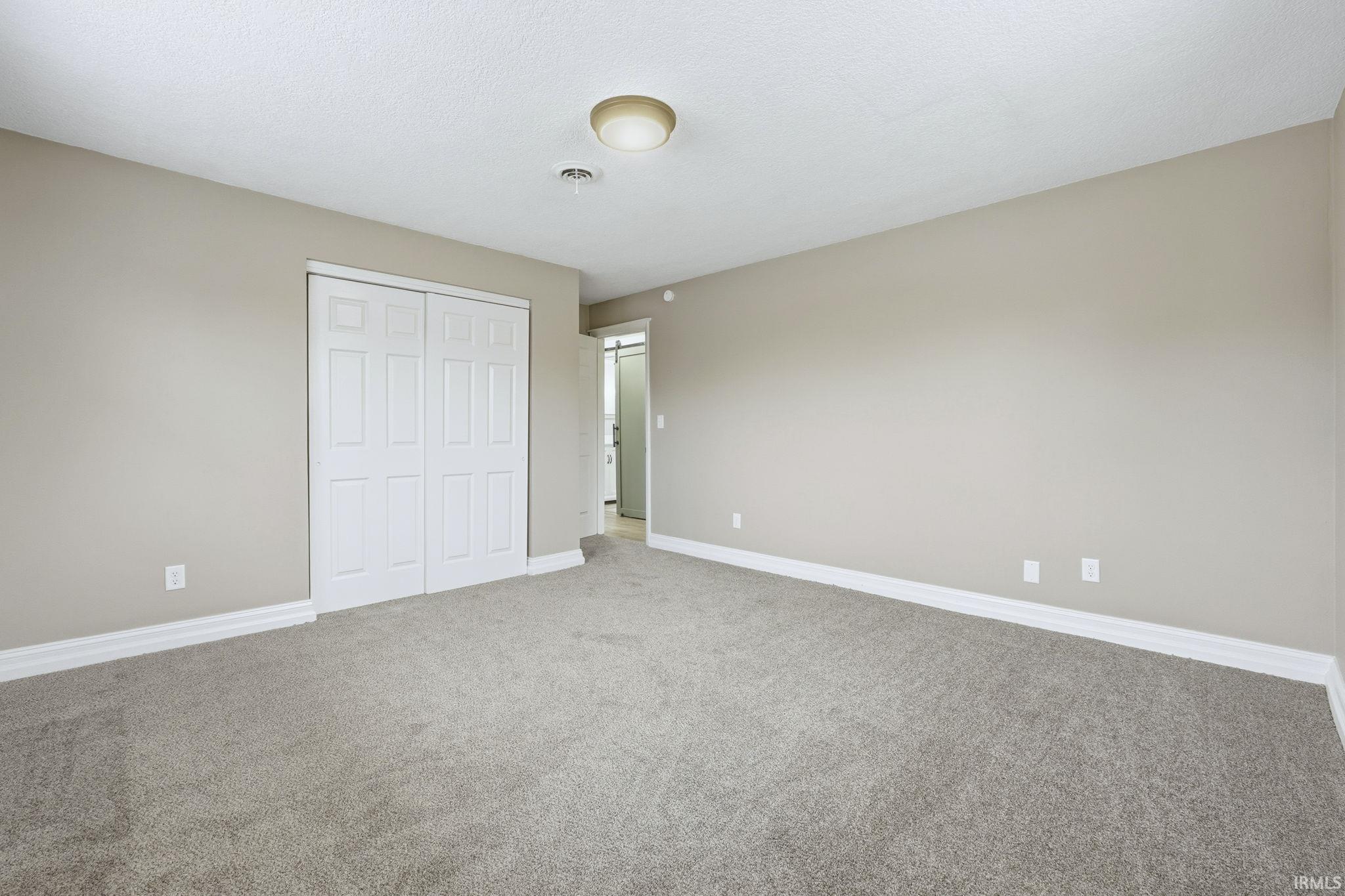 Unfurnished bedroom featuring a closet, carpet floors, and a textured ceiling