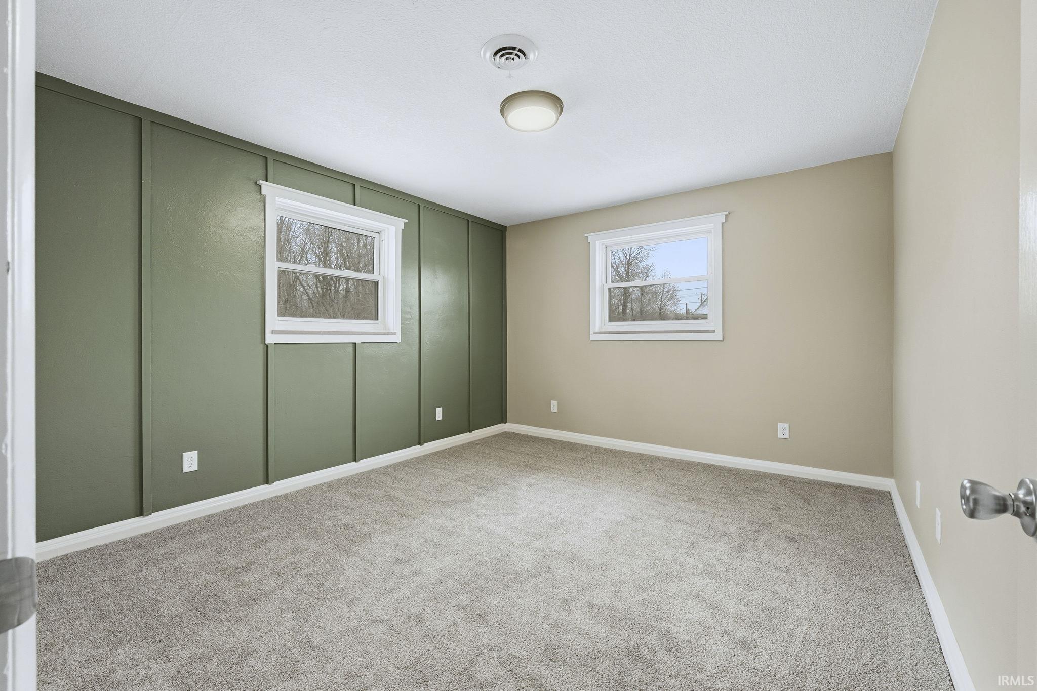 Carpeted spare room with a decorative wall and baseboards