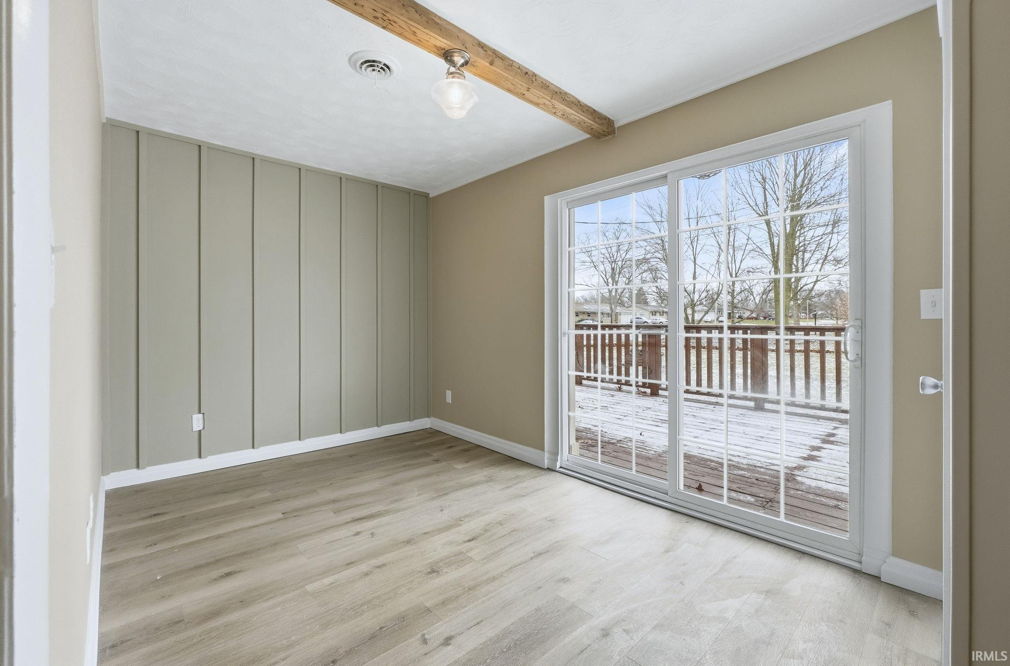 Unfurnished room with beam ceiling and light wood-type flooring