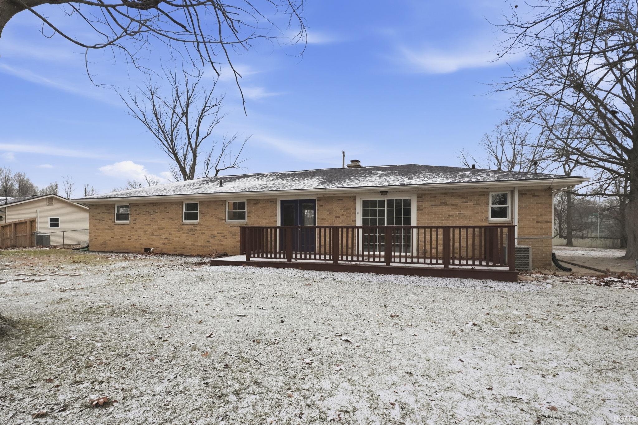 Rear view of property featuring brick siding and a deck