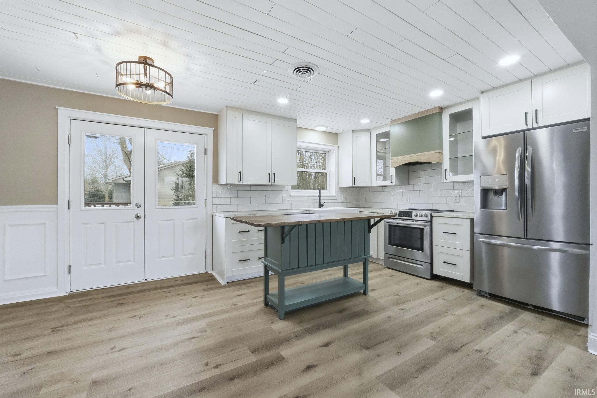 Kitchen featuring white cabinets, stainless steel appliances, glass insert cabinets, butcher block countertops, and wooden ceiling