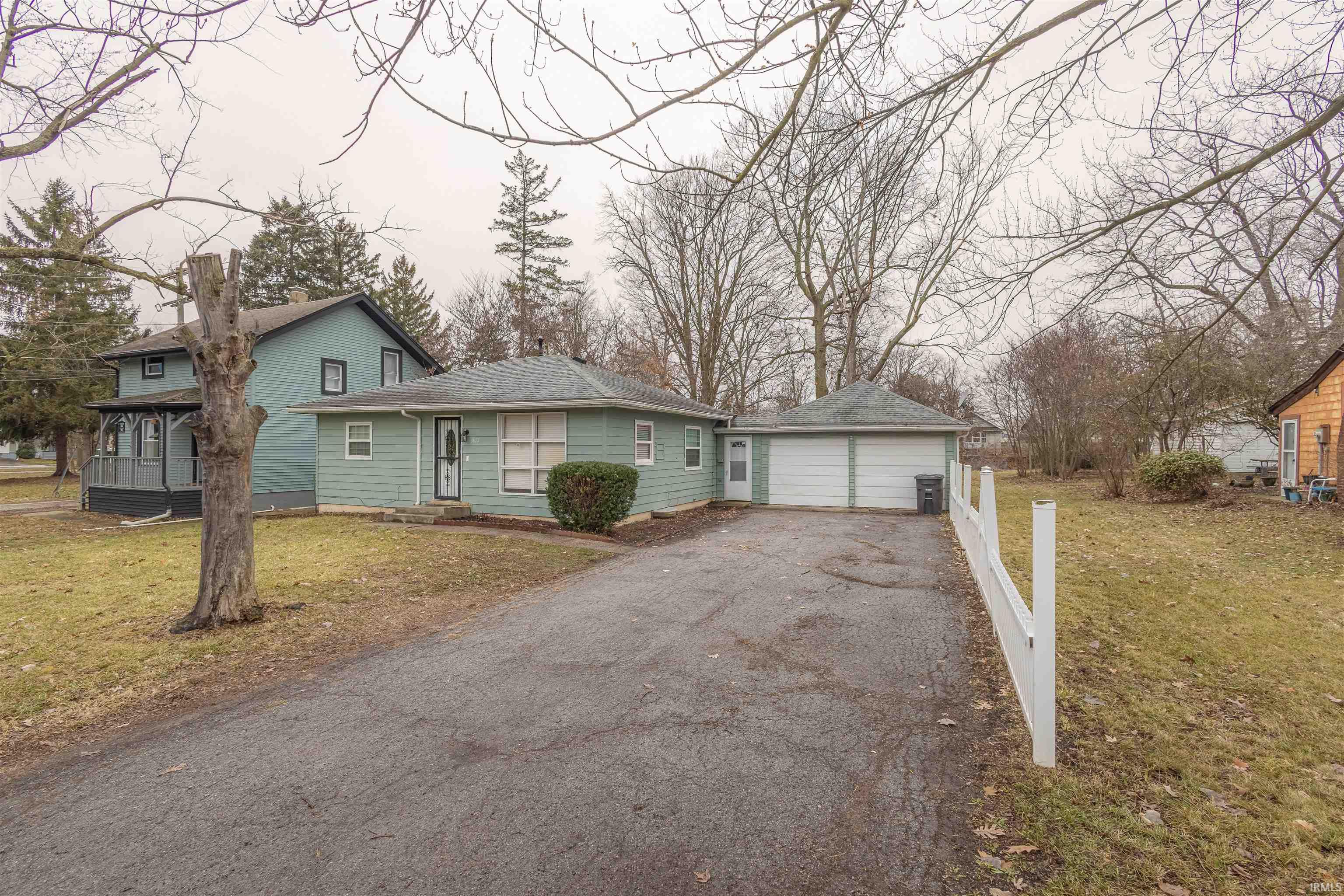 View of front facade with a front yard, an outbuilding, driveway, and roof with shingles