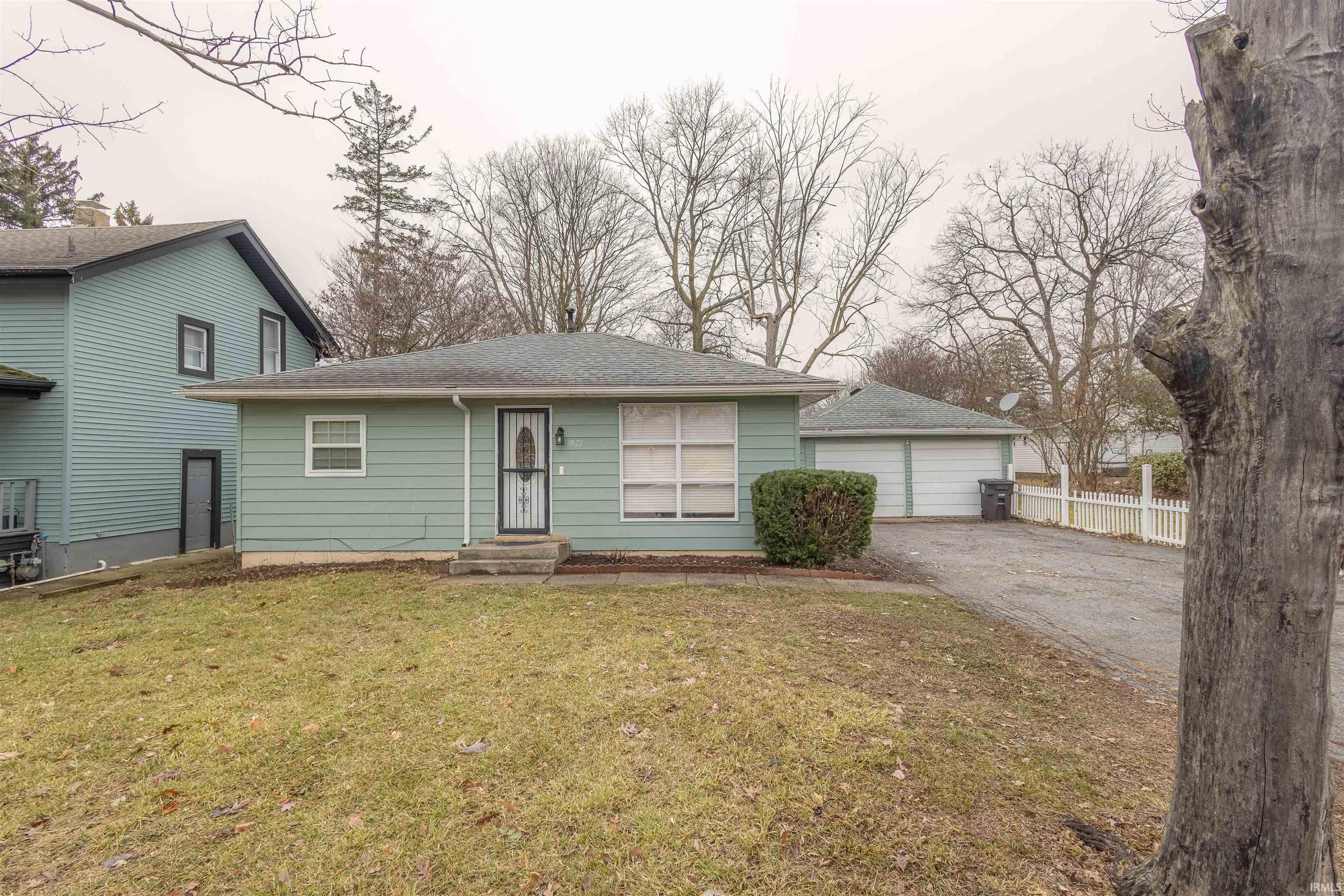 View of front facade featuring a shingled roof, a garage, and asphalt driveway