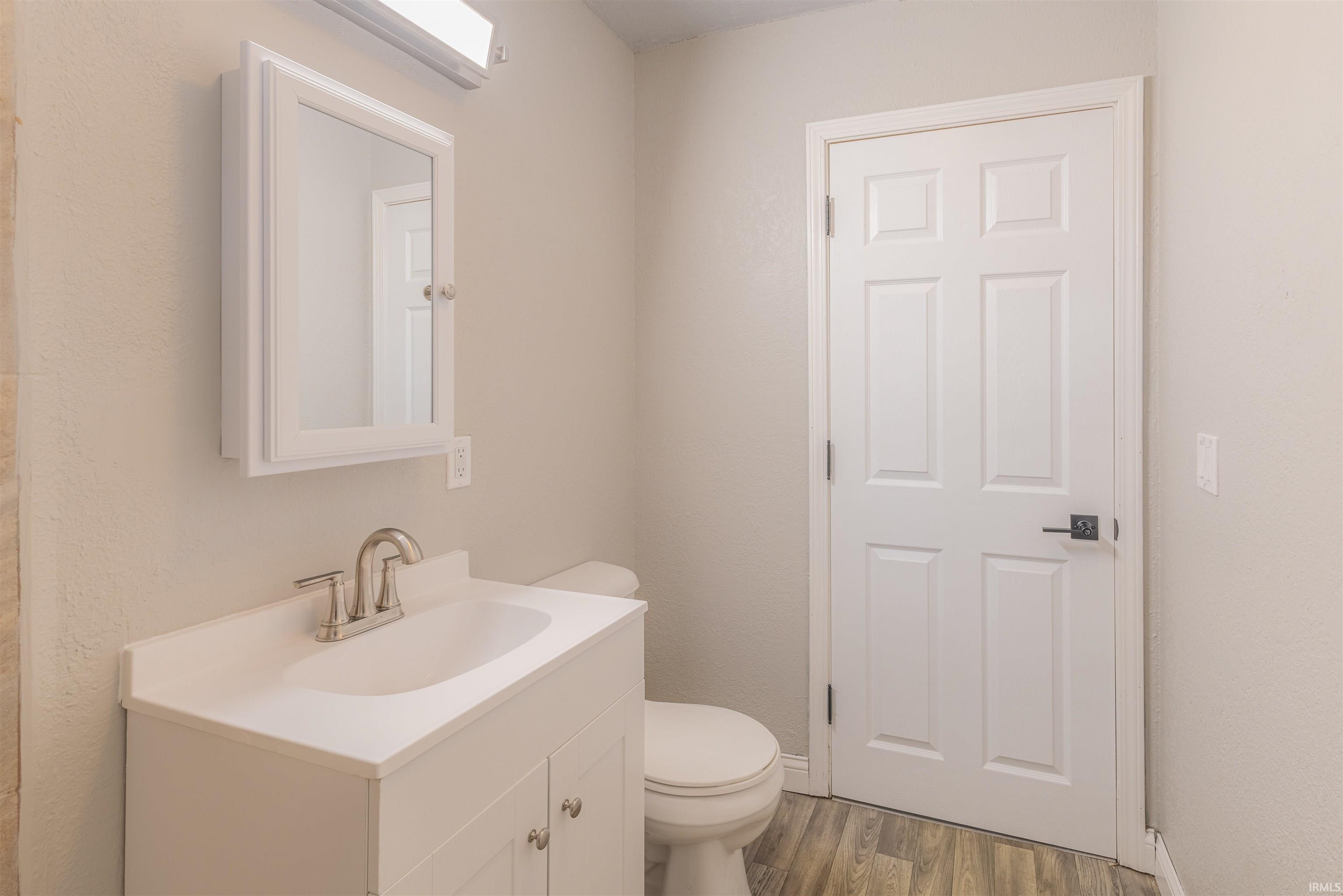 Half bathroom featuring vanity and wood finished floors