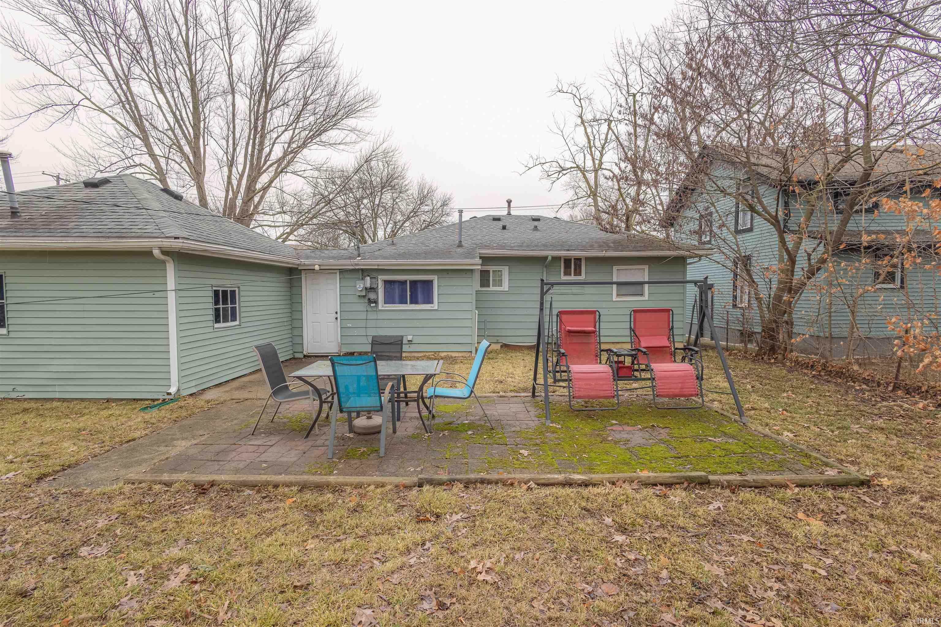 Rear view of house featuring a patio area, a lawn, and roof with shingles