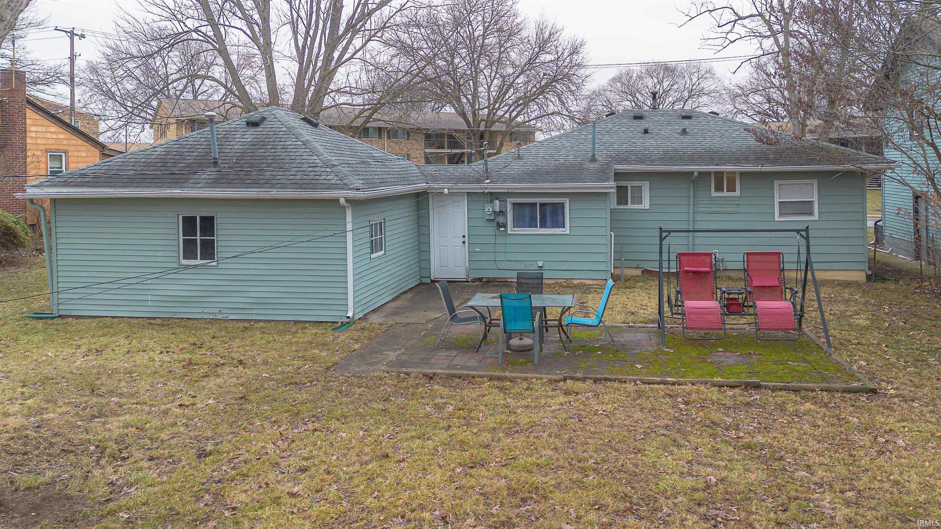 Back of house featuring a yard, a patio area, and roof with shingles
