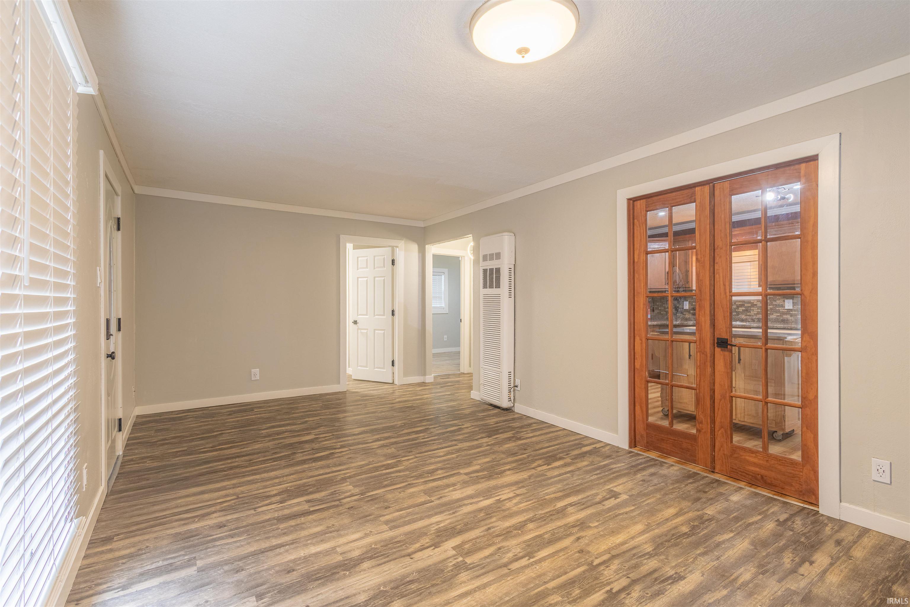 Spare room featuring wood finished floors, a heating unit, and crown molding