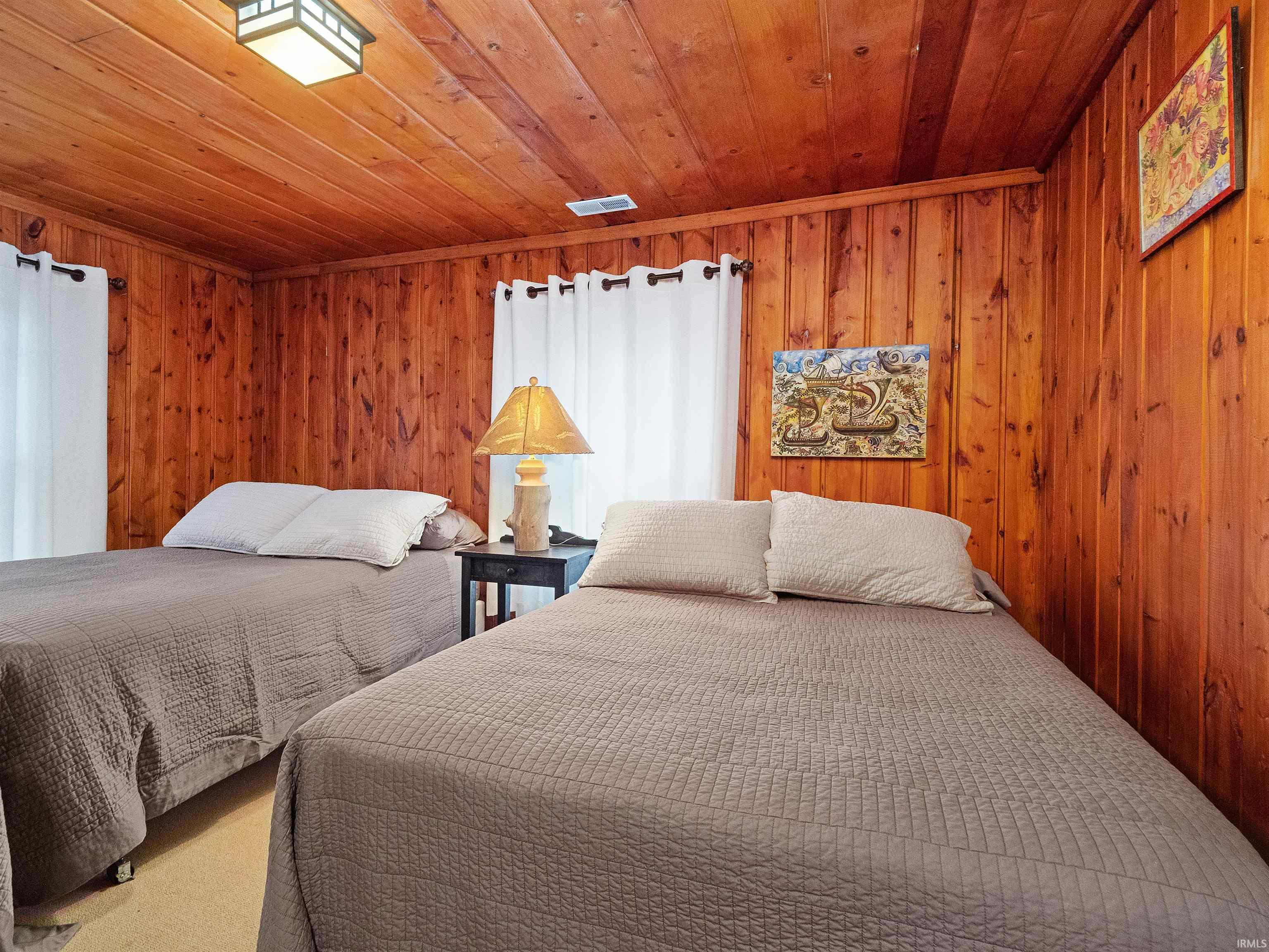 Bedroom with wooden ceiling, wooden walls, and carpet flooring