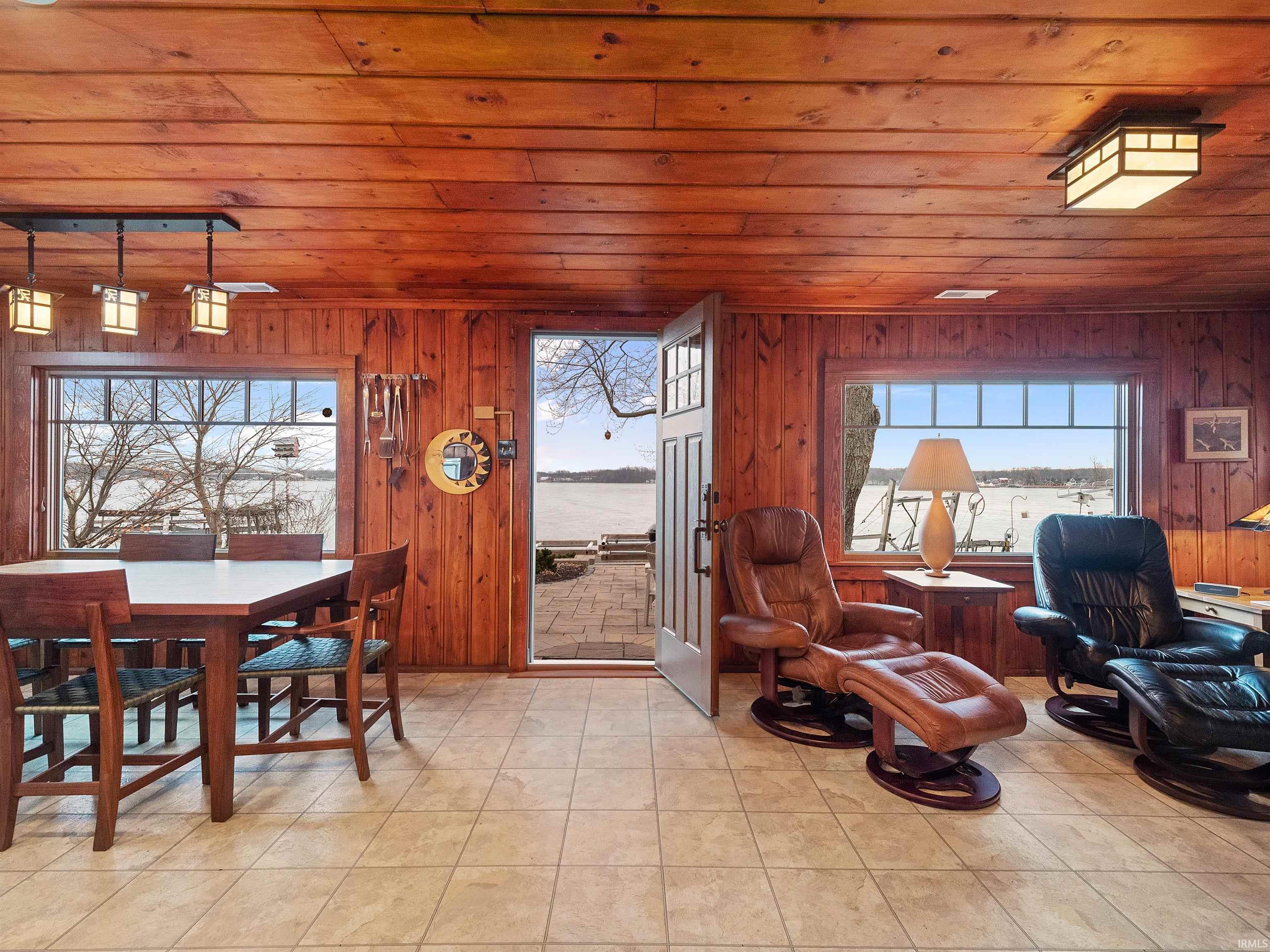 Tiled dining space featuring wood walls, wooden ceiling, and a water view