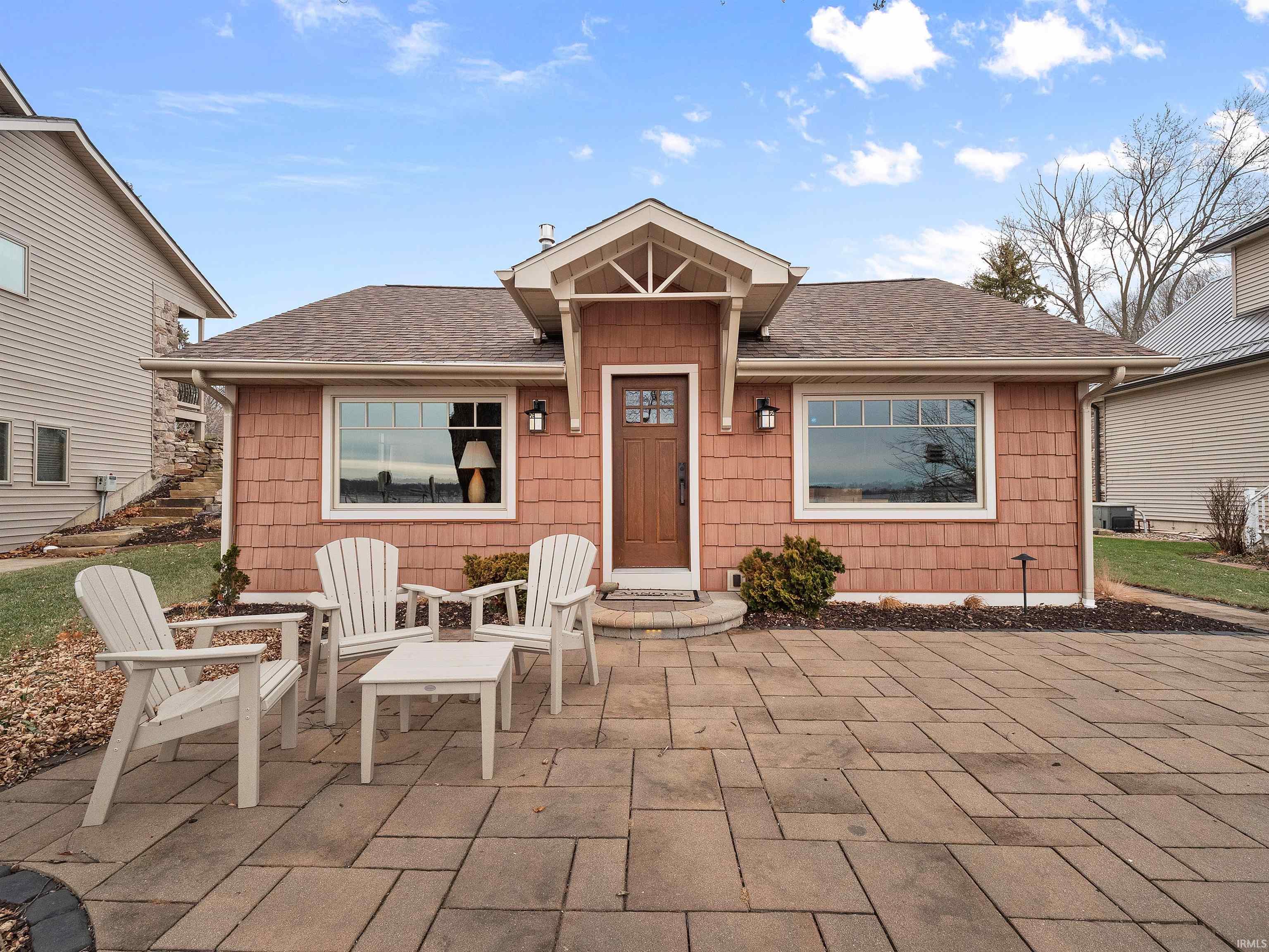 View of front of home with a shingled roof and a patio area