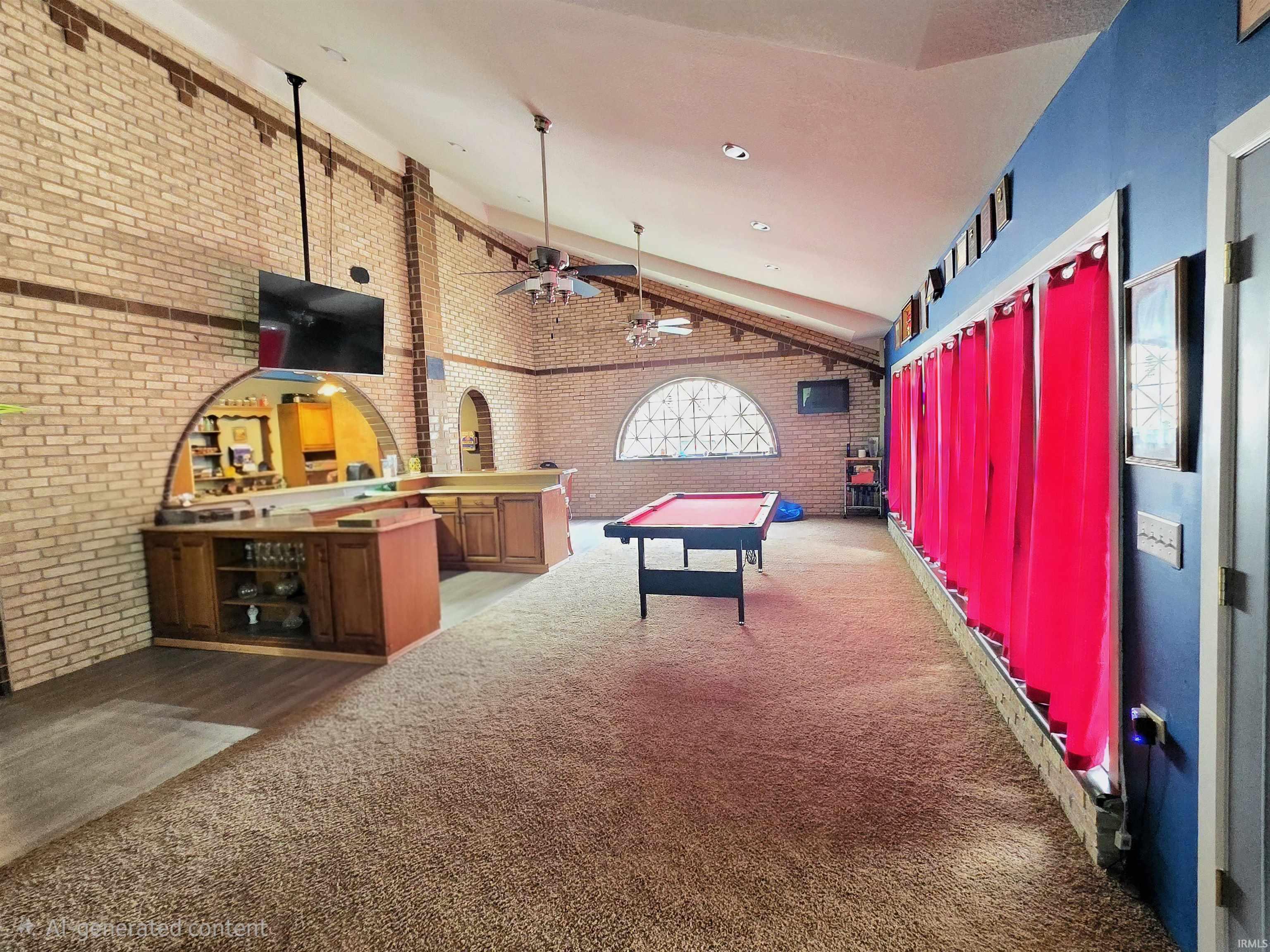 Expansive entertainment space featuring vaulted ceilings, exposed brick walls, a built-in bar with wood cabinetry, and an arched pass-through window