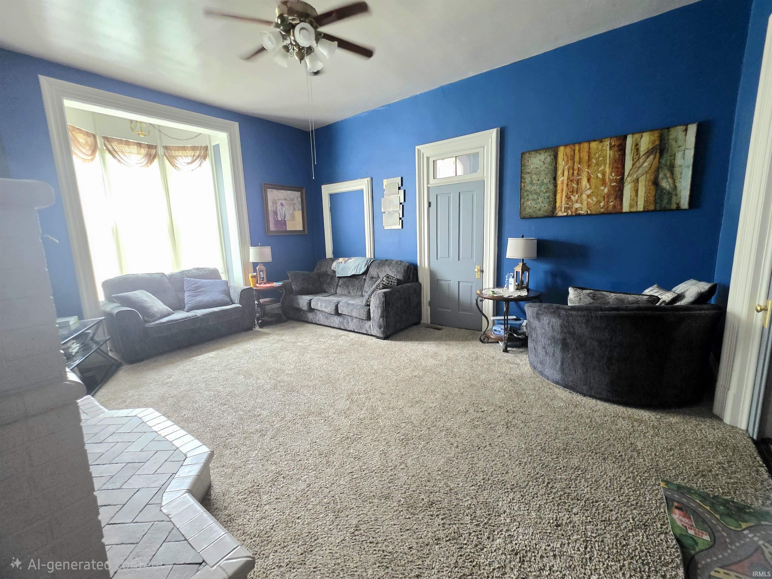 Spacious room featuring broadloom carpeting, a ceiling fan with light fixture, a large window with white trim, and a grey interior door with transom window