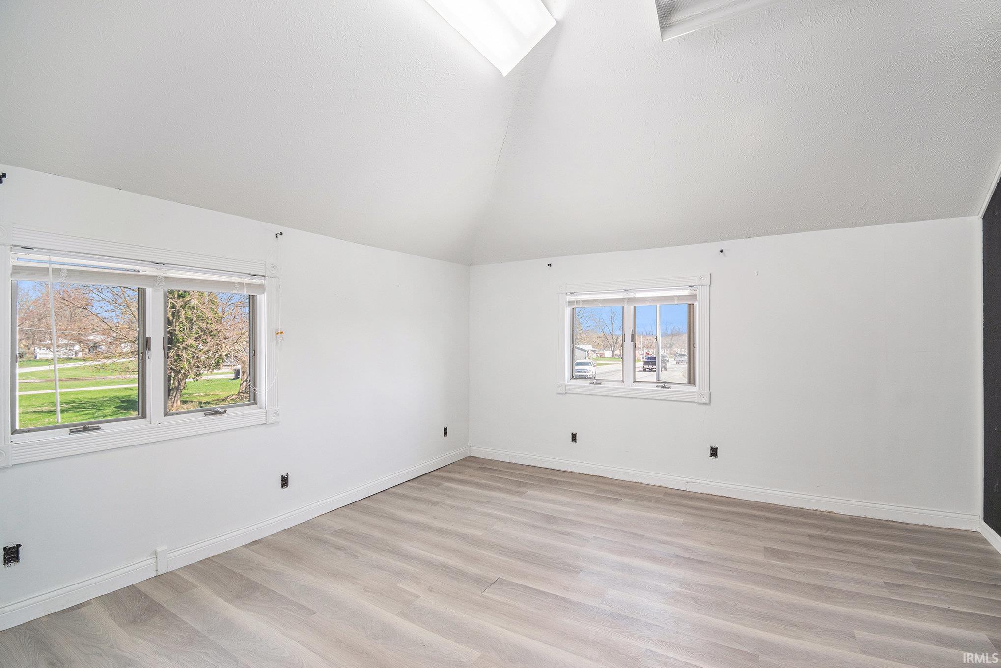 Empty room featuring light wood-type flooring and lofted ceiling
