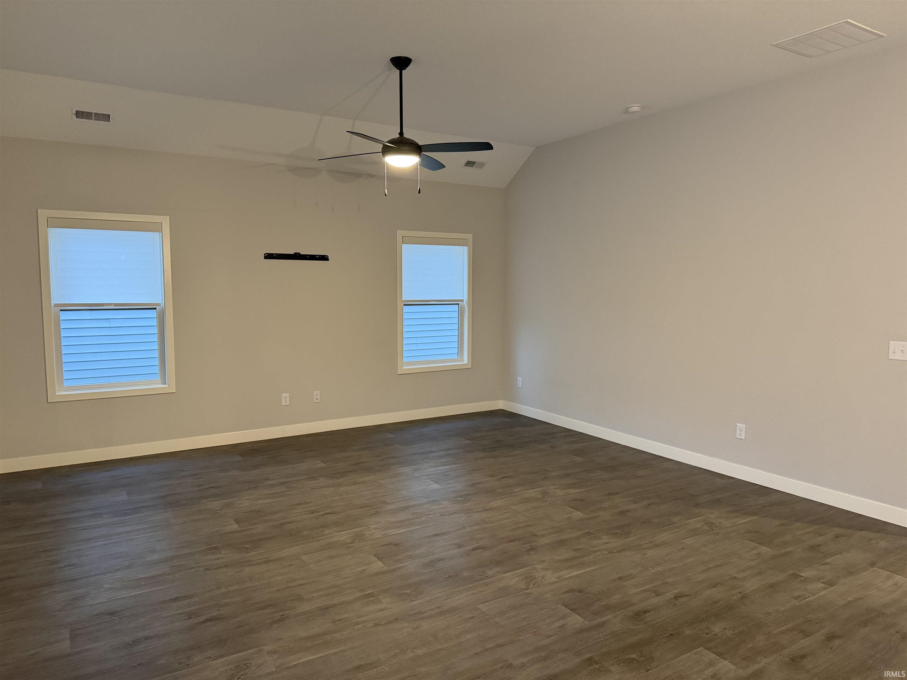 Living room with dark wood-style flooring, vaulted ceiling, and ceiling fan