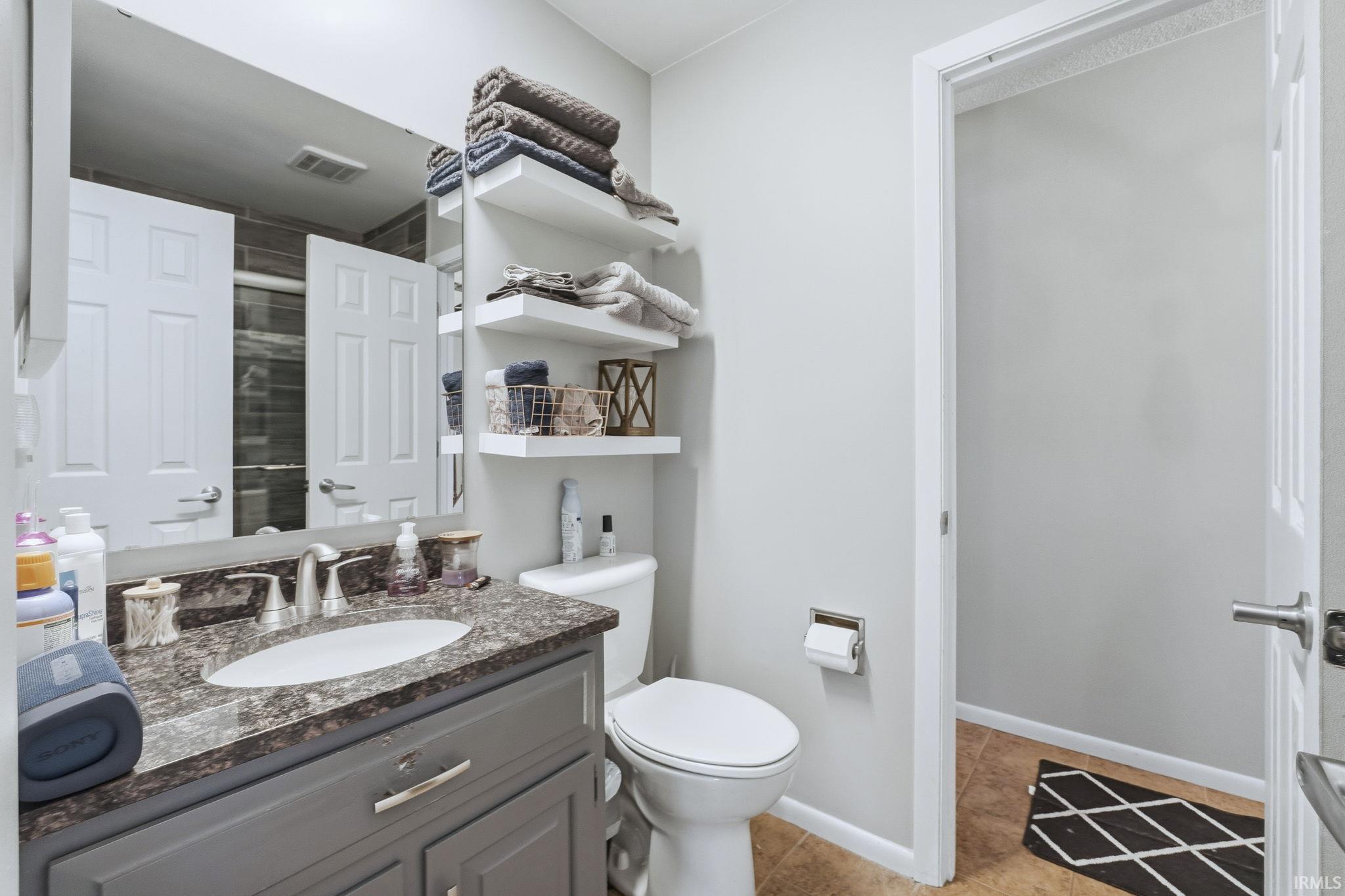 Bathroom with vanity, a shower, and light tile patterned flooring