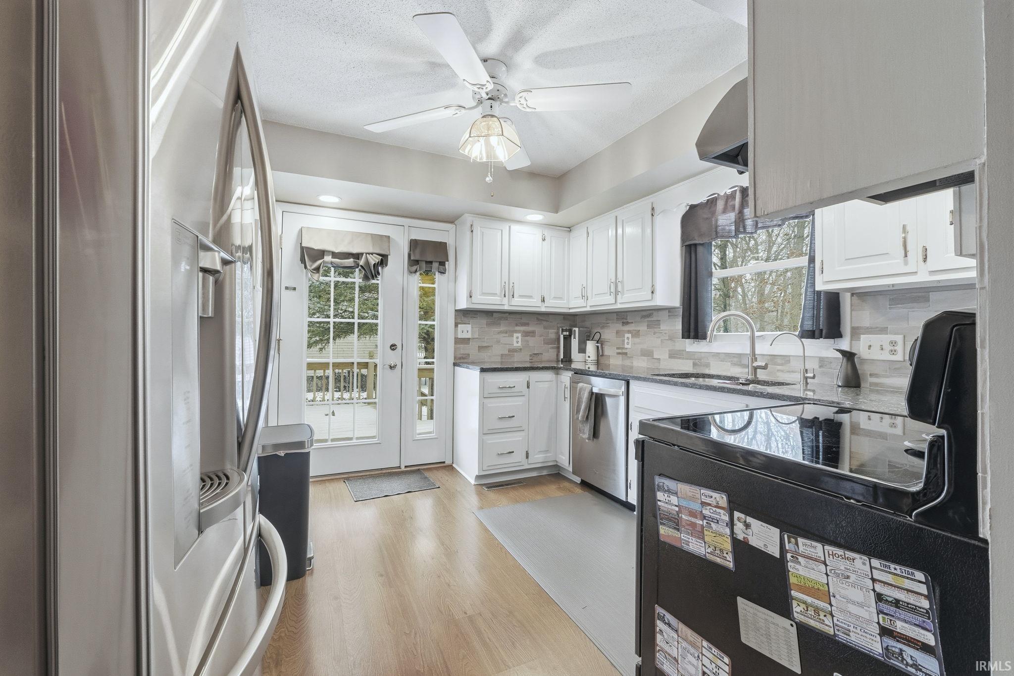 Kitchen featuring appliances with stainless steel finishes, white cabinets, plenty of natural light, and dark stone counters