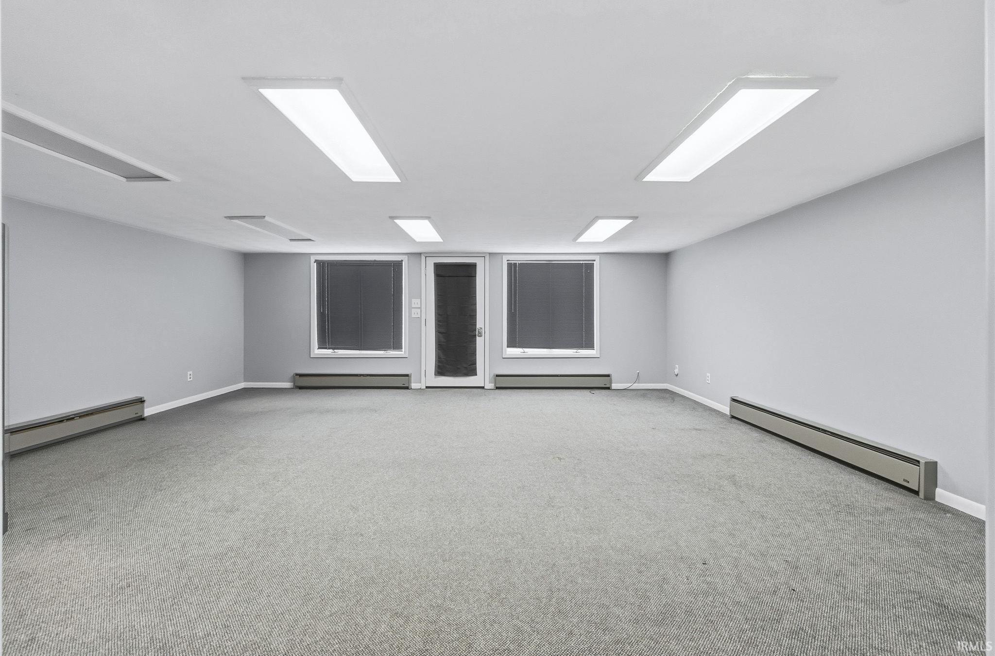 Empty room featuring baseboard heating and light carpet