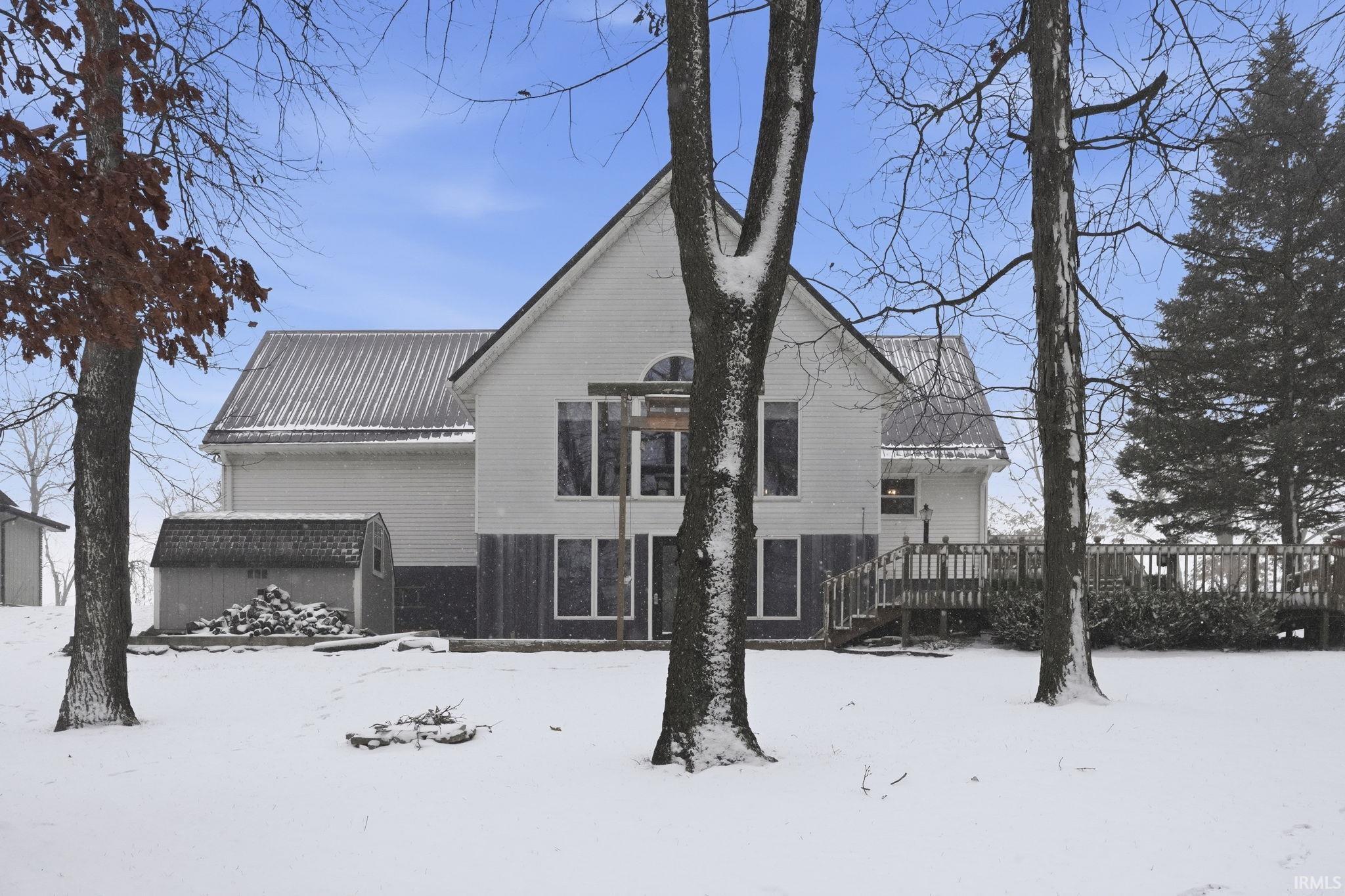 Snow covered back of property with a wooden deck