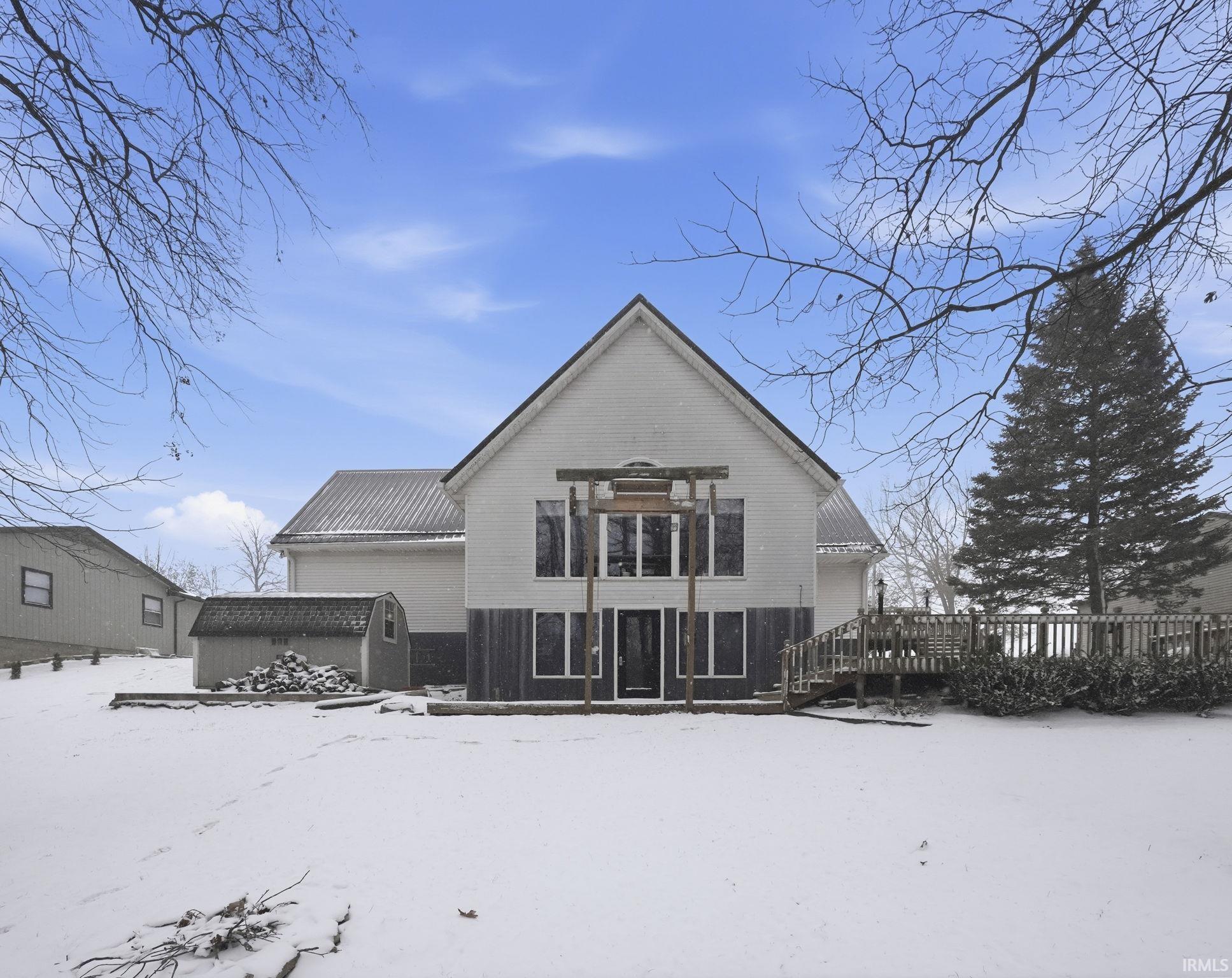 Snow covered rear of property with a wooden deck