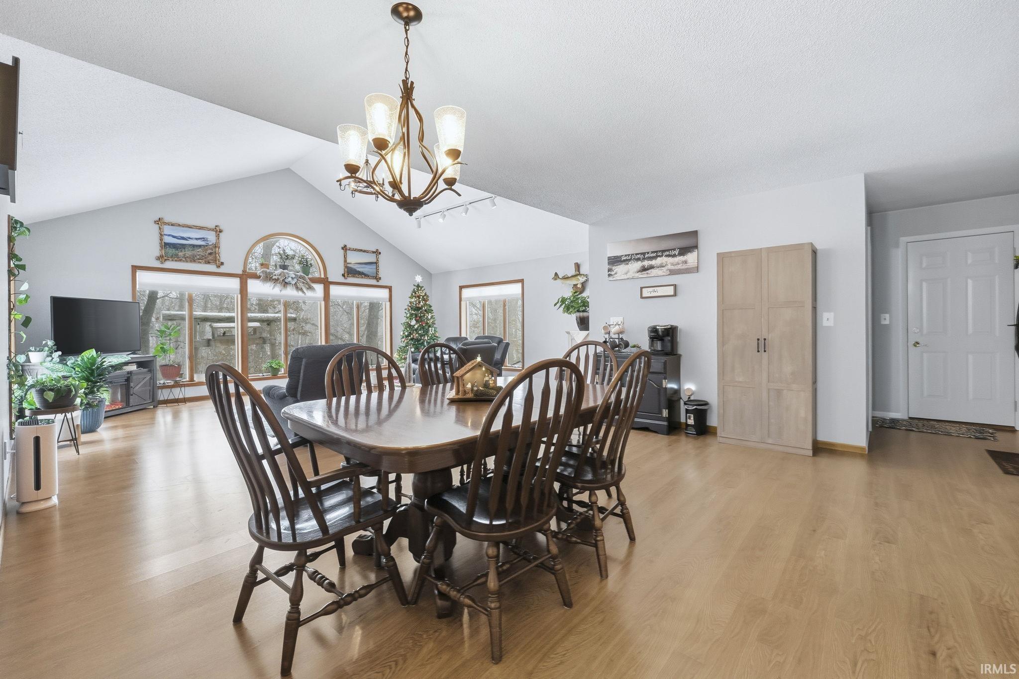 Dining space with a chandelier, light wood-style flooring, and lofted ceiling