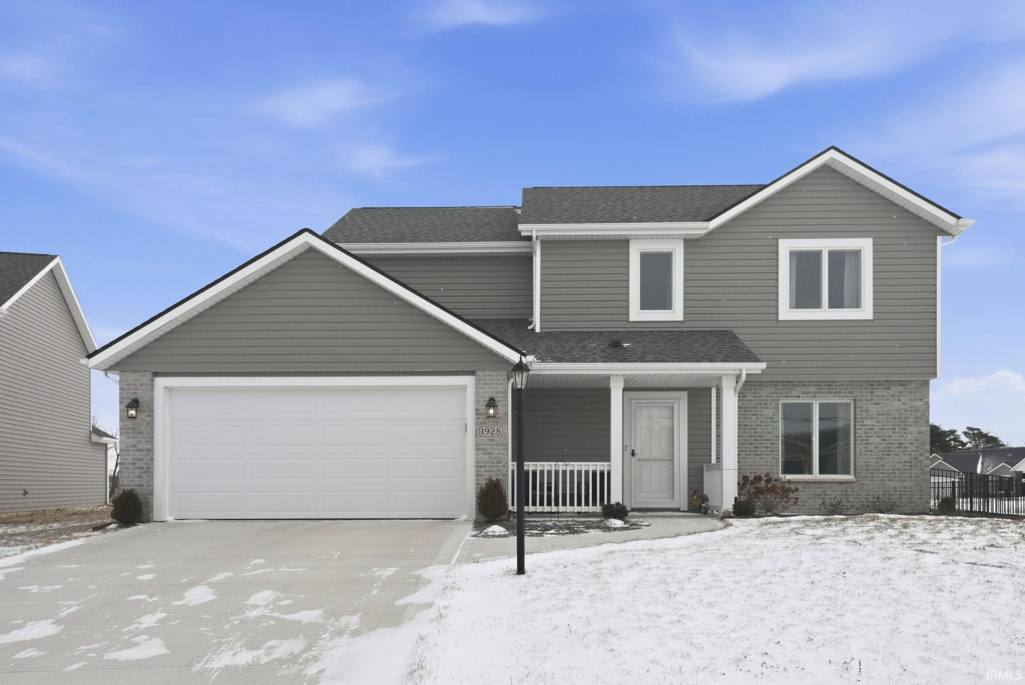 Traditional-style home featuring brick siding, a porch, concrete driveway, a garage, and a shingled roof