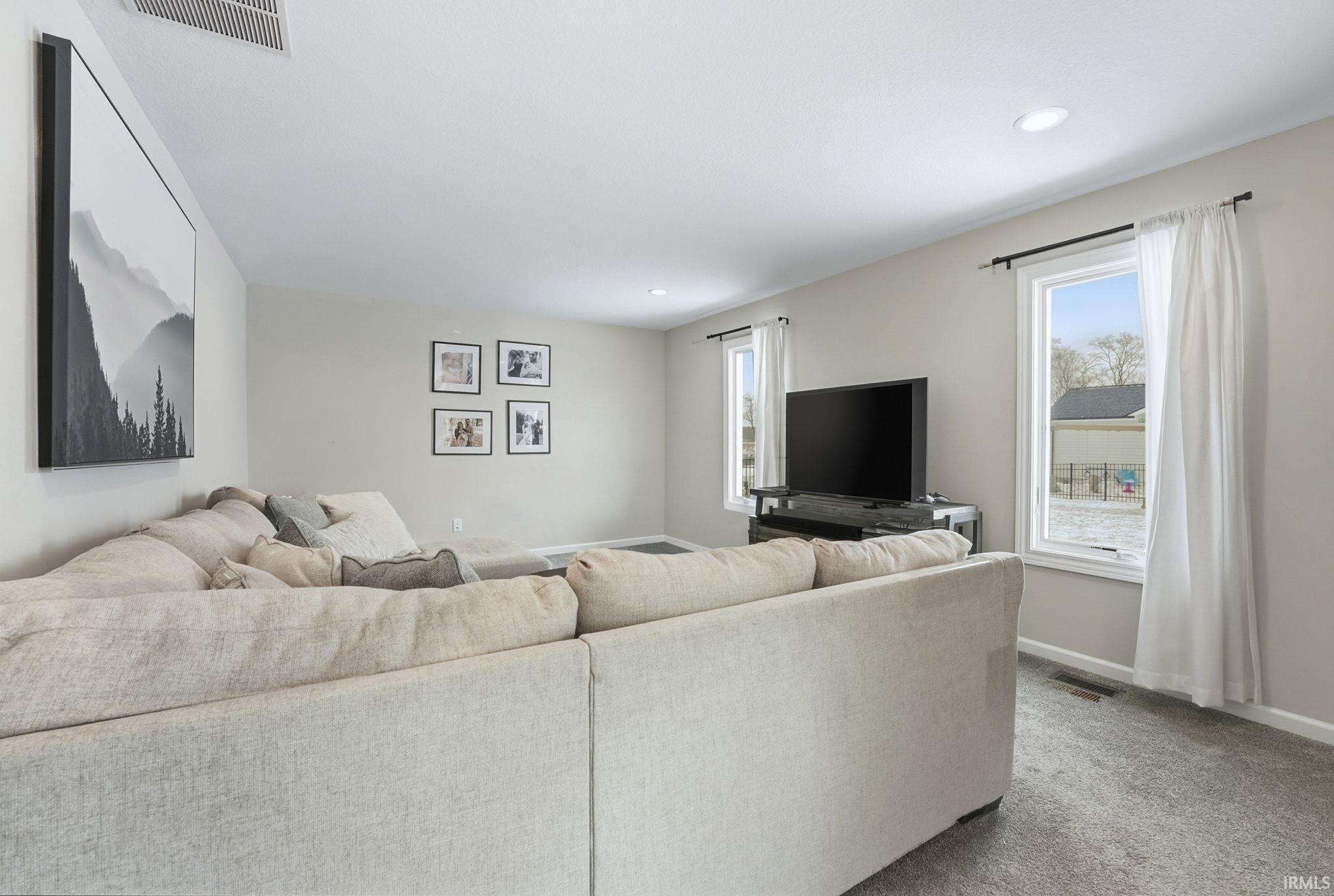 Carpeted living area with baseboards and recessed lighting