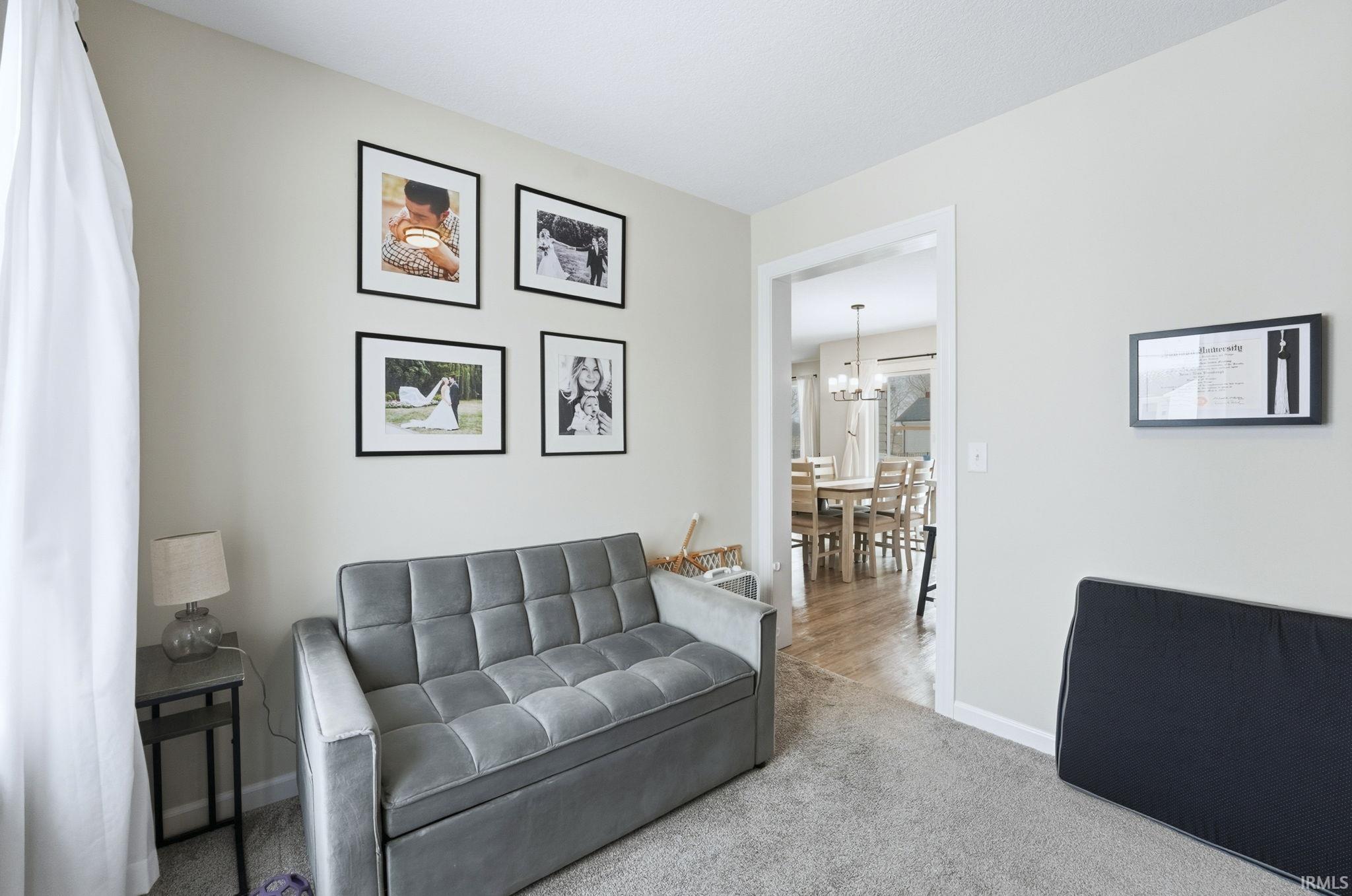 Carpeted living area featuring baseboards and a chandelier