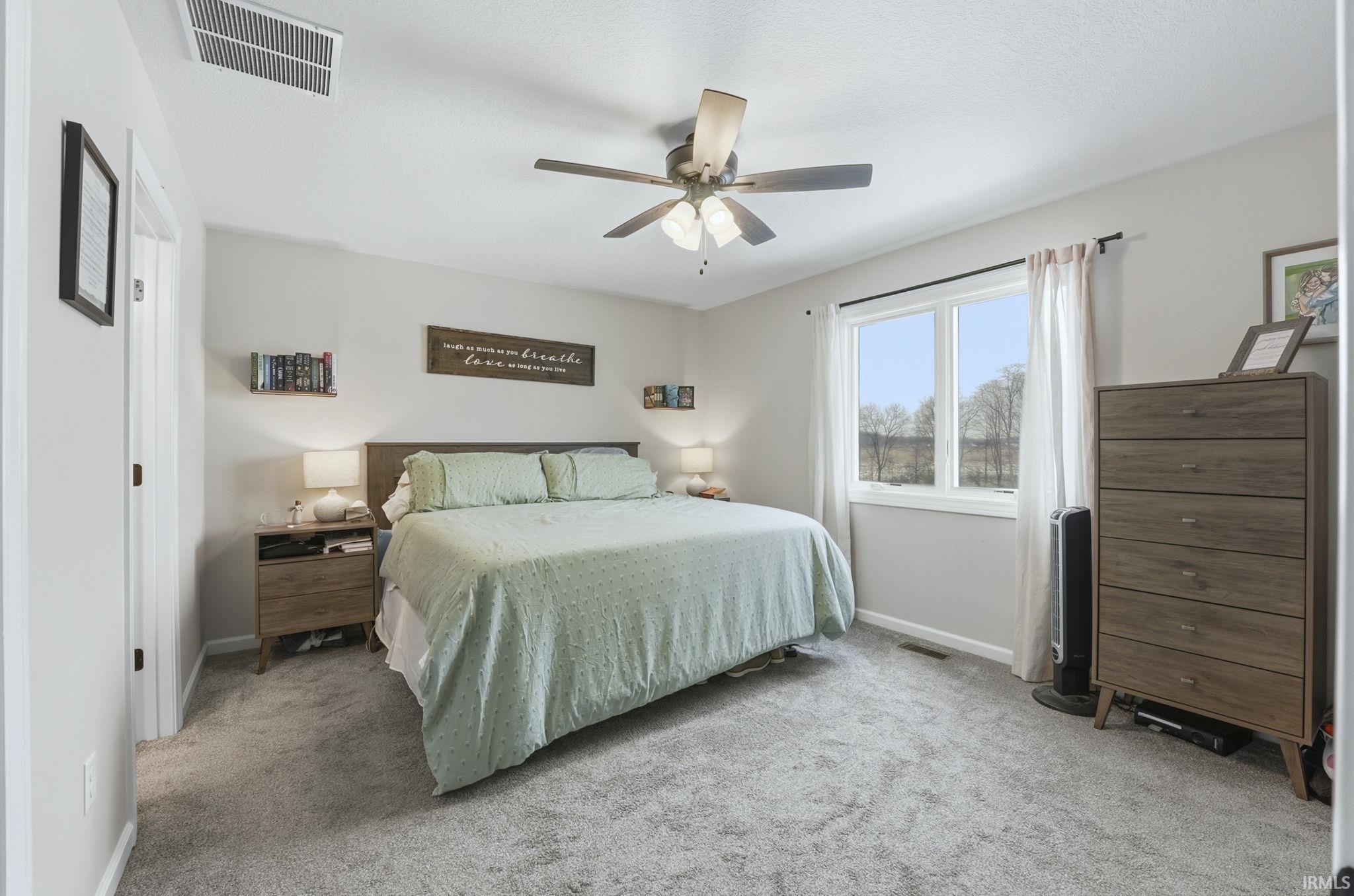Bedroom with light carpet and a ceiling fan