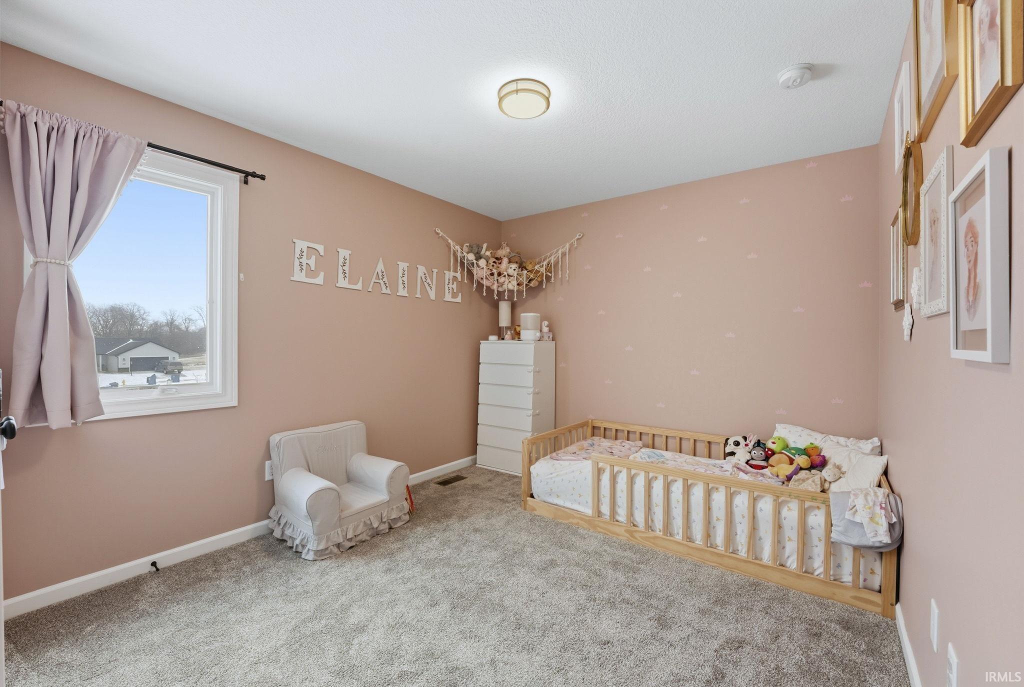 Bedroom featuring a nursery area and carpet flooring