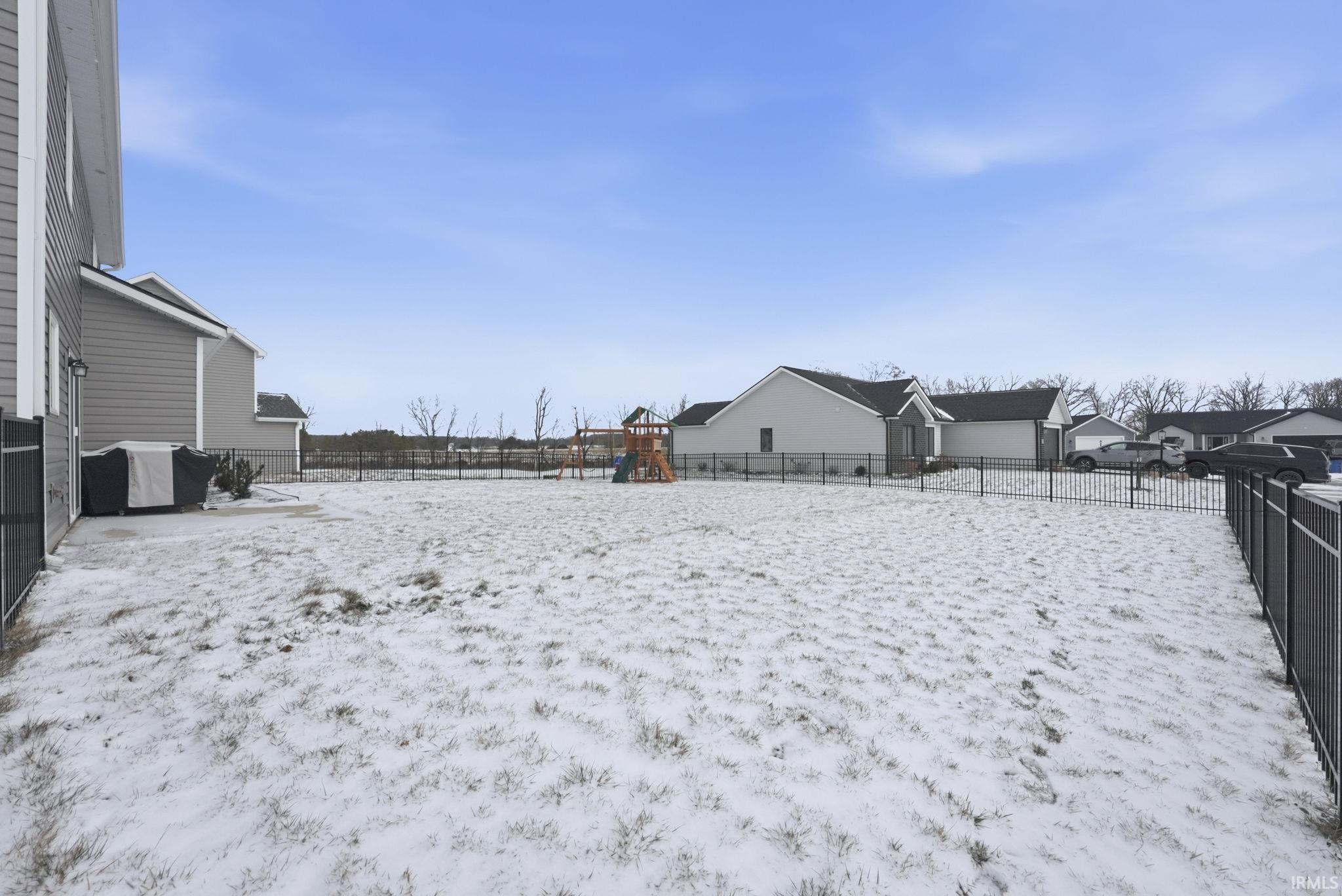Yard covered in snow featuring a playground and a fenced backyard