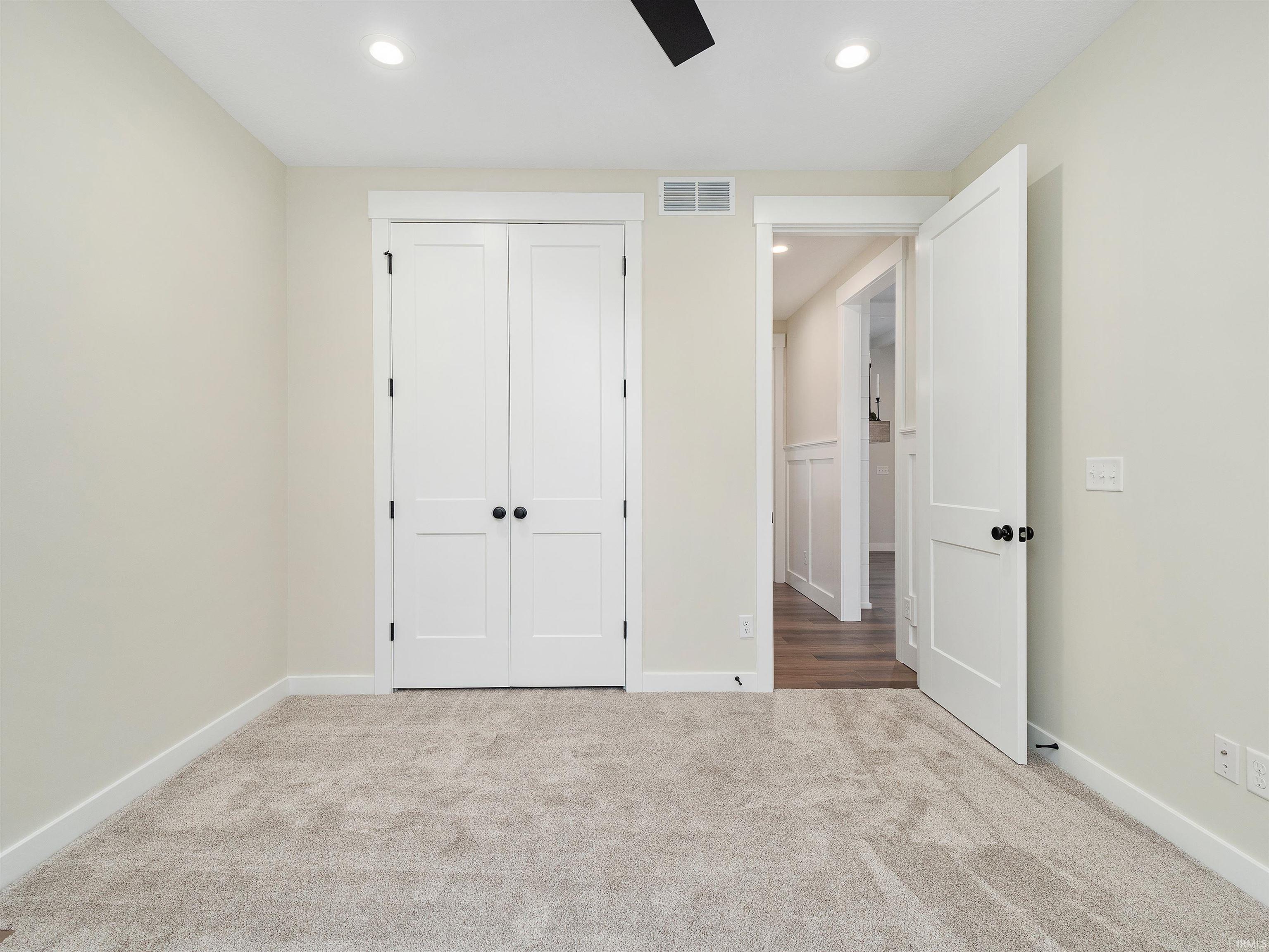 Neutral carpet, custom closet system, 8' high wood paneled doors, recessed lighting, and ceiling fan